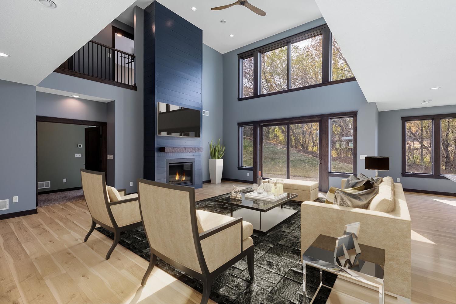 Modern living room with blue walls, fireplace, large windows, light wood floors, and neutral furniture.