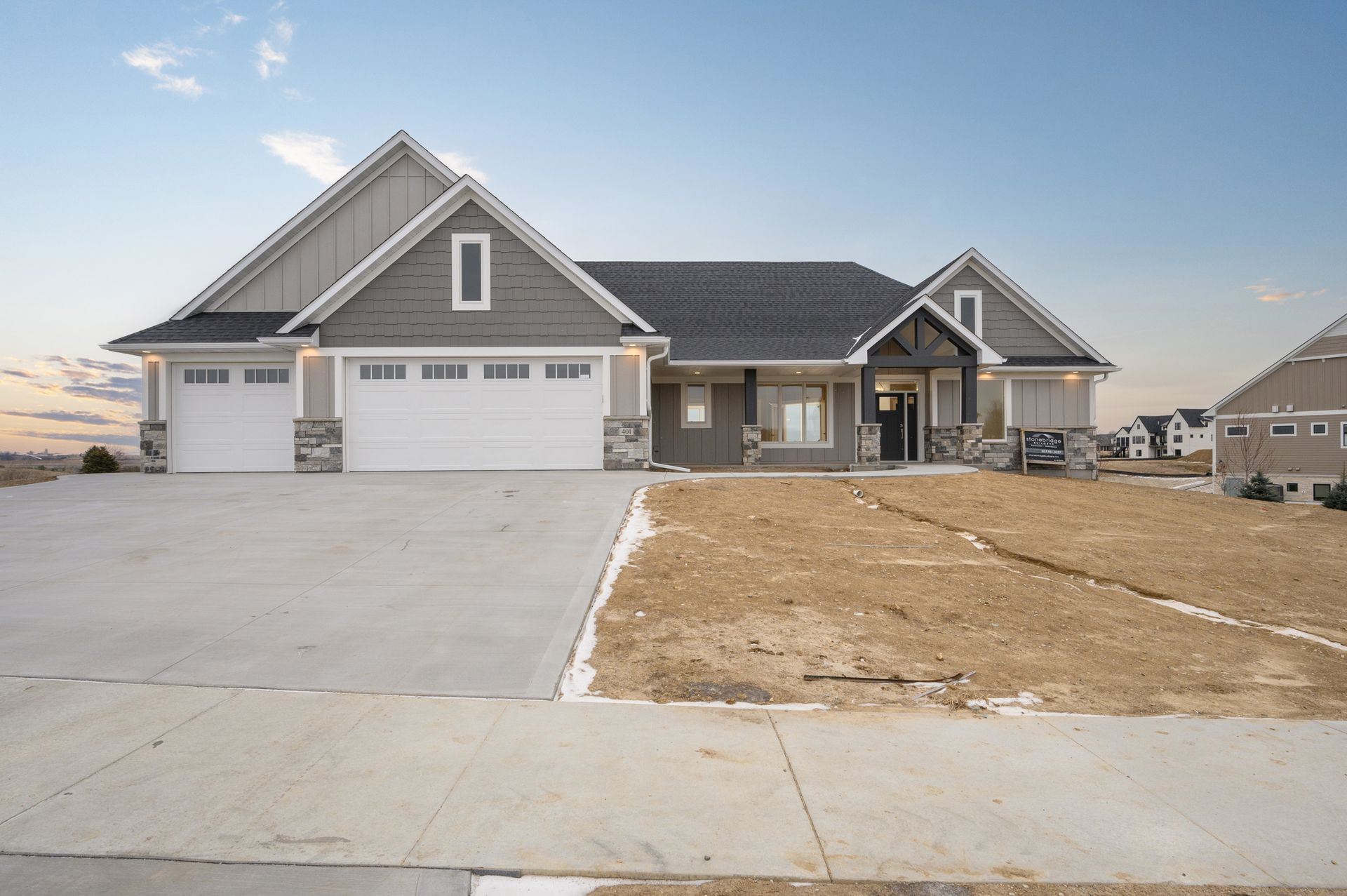 Suburban home with gray siding, white garage doors, and a concrete driveway.