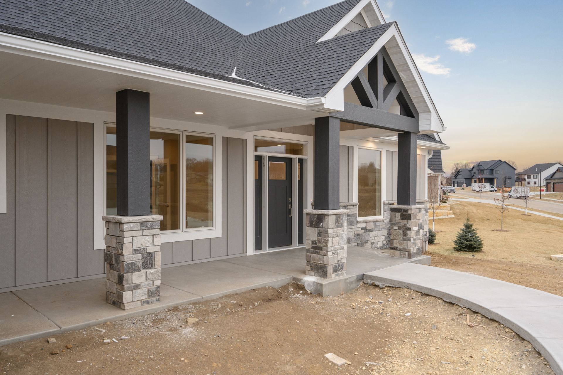Gray house with a front porch, stone pillars, and gray roof.
