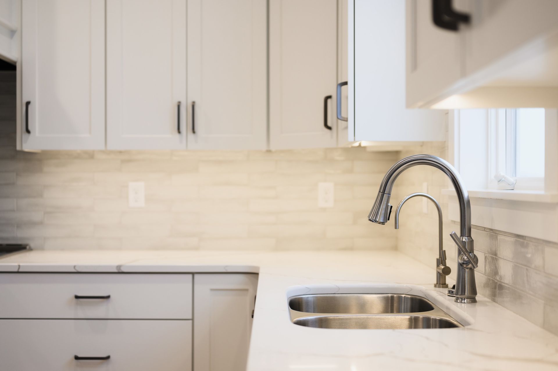Kitchen with white cabinets, stainless steel sink, and faucet.