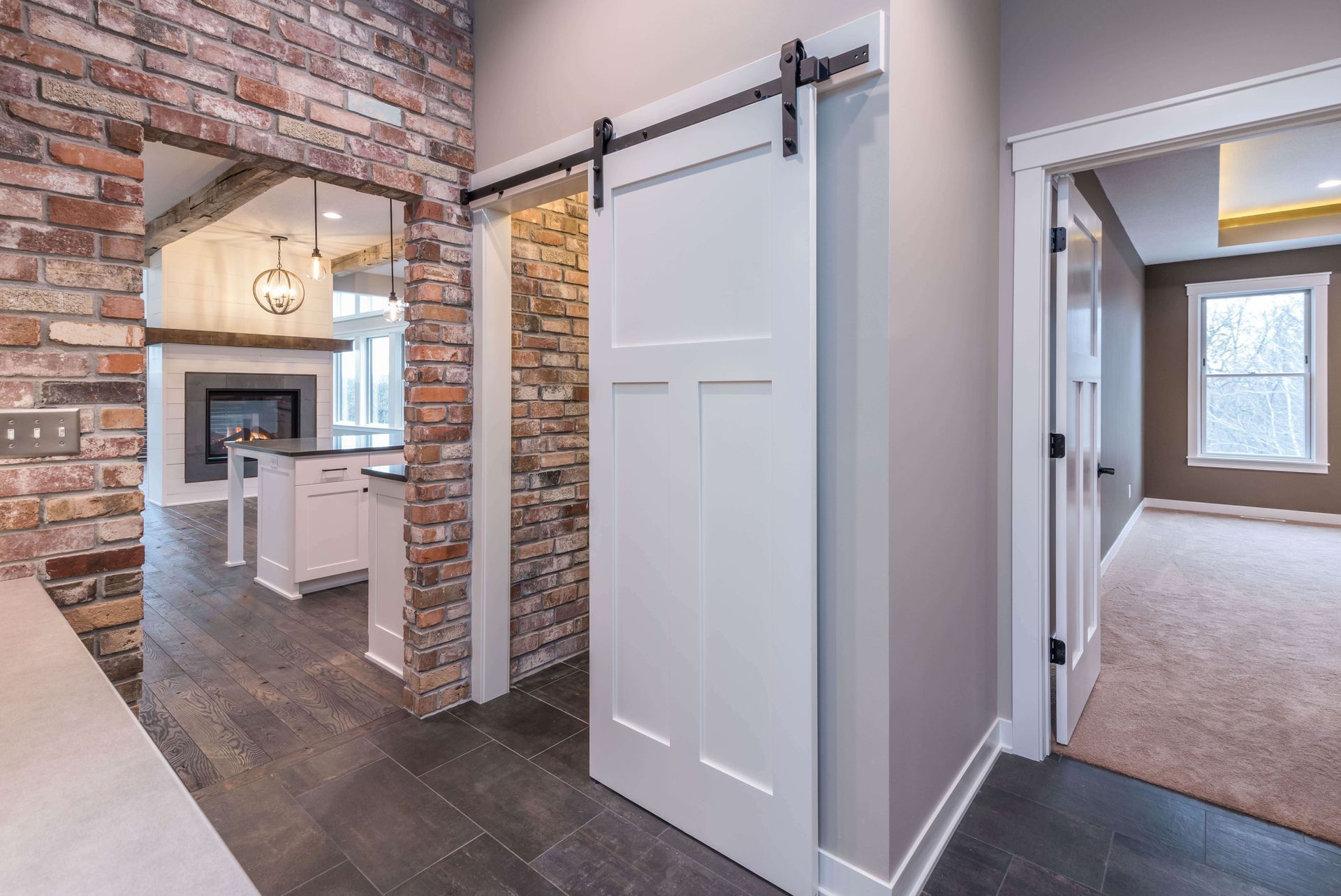 Interior with brick archway, white sliding door on track, and doorway to a bedroom.