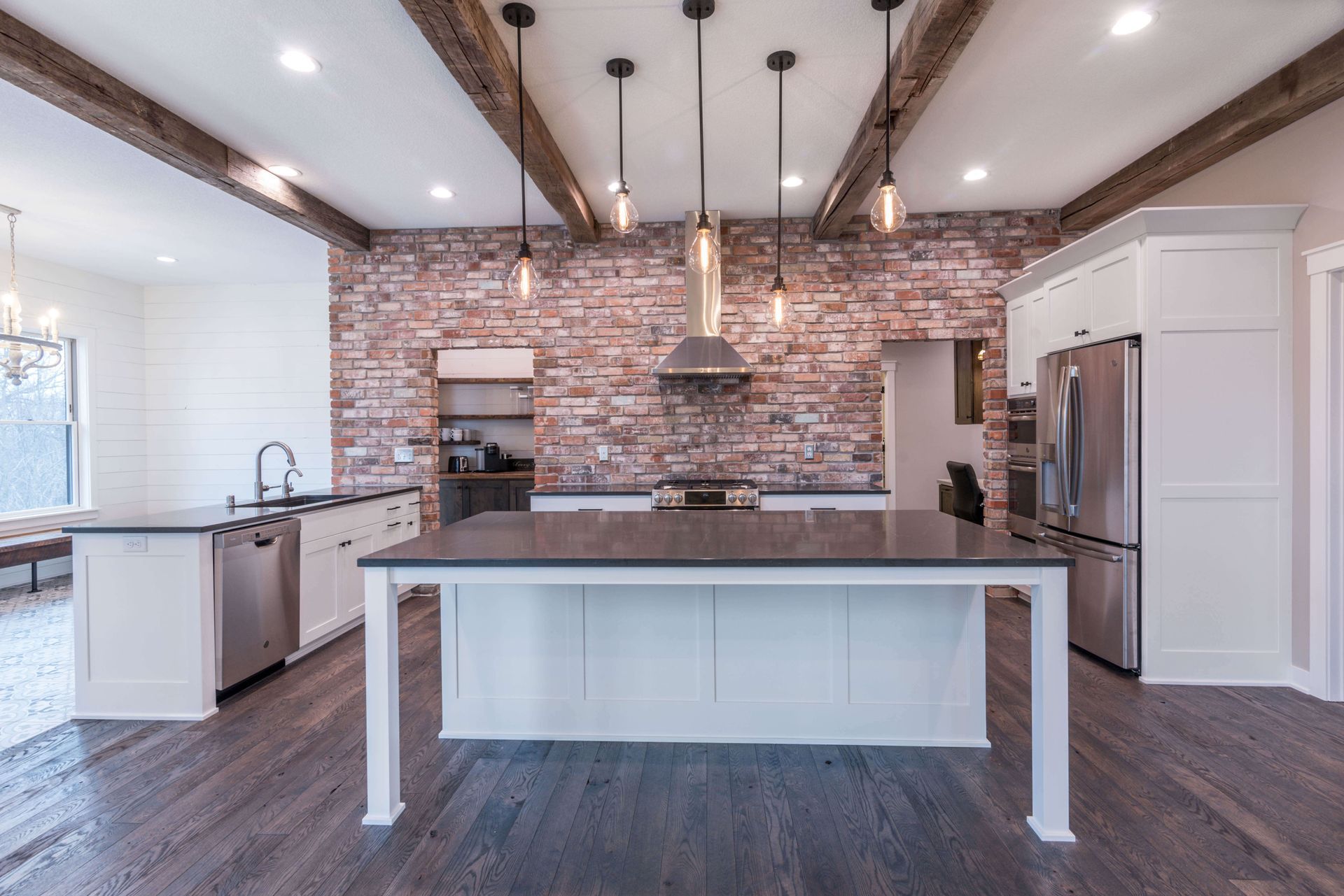 Kitchen with exposed brick wall, white cabinets, and island with gray countertop.