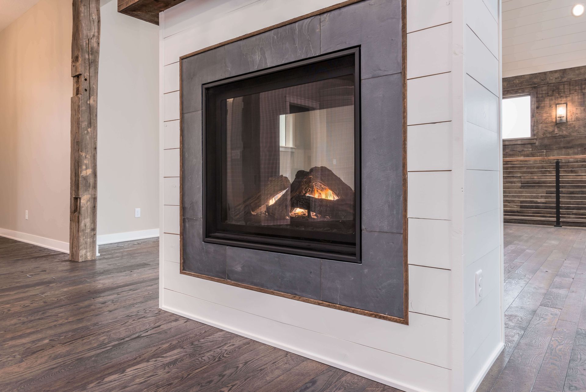 Modern fireplace with dark metal surround, white shiplap, and a wooden beam.