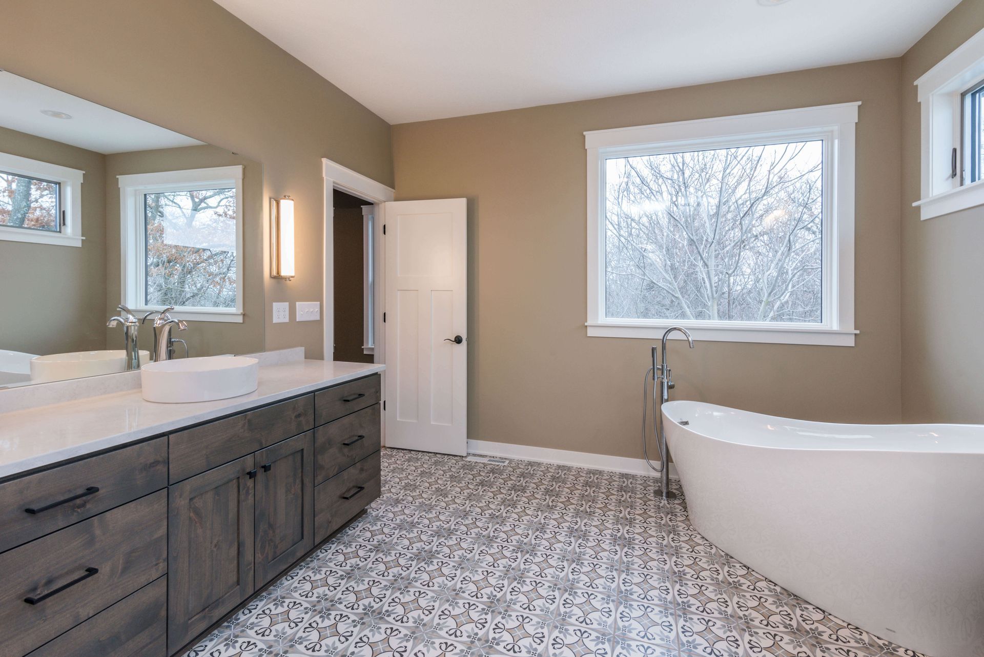 Modern bathroom with a freestanding tub, vanity, and patterned tile floor.
