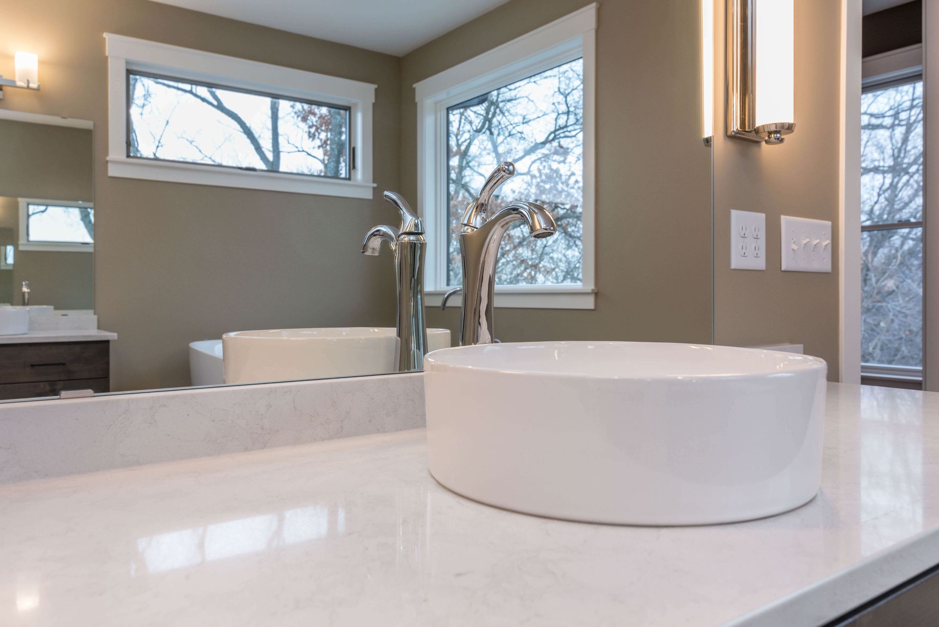 Modern bathroom with a white sink, chrome faucet, and neutral walls.