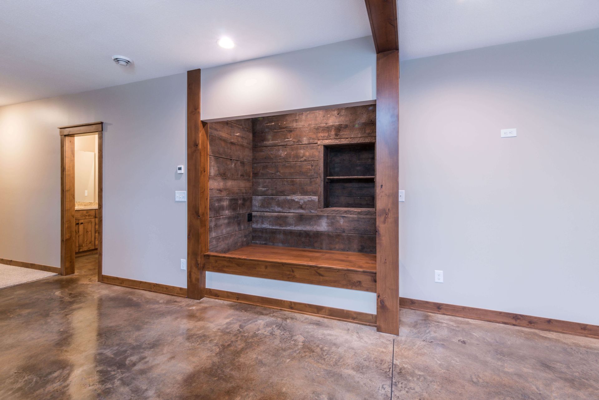 Empty room with concrete floor, built-in wooden shelving, and brown trim.