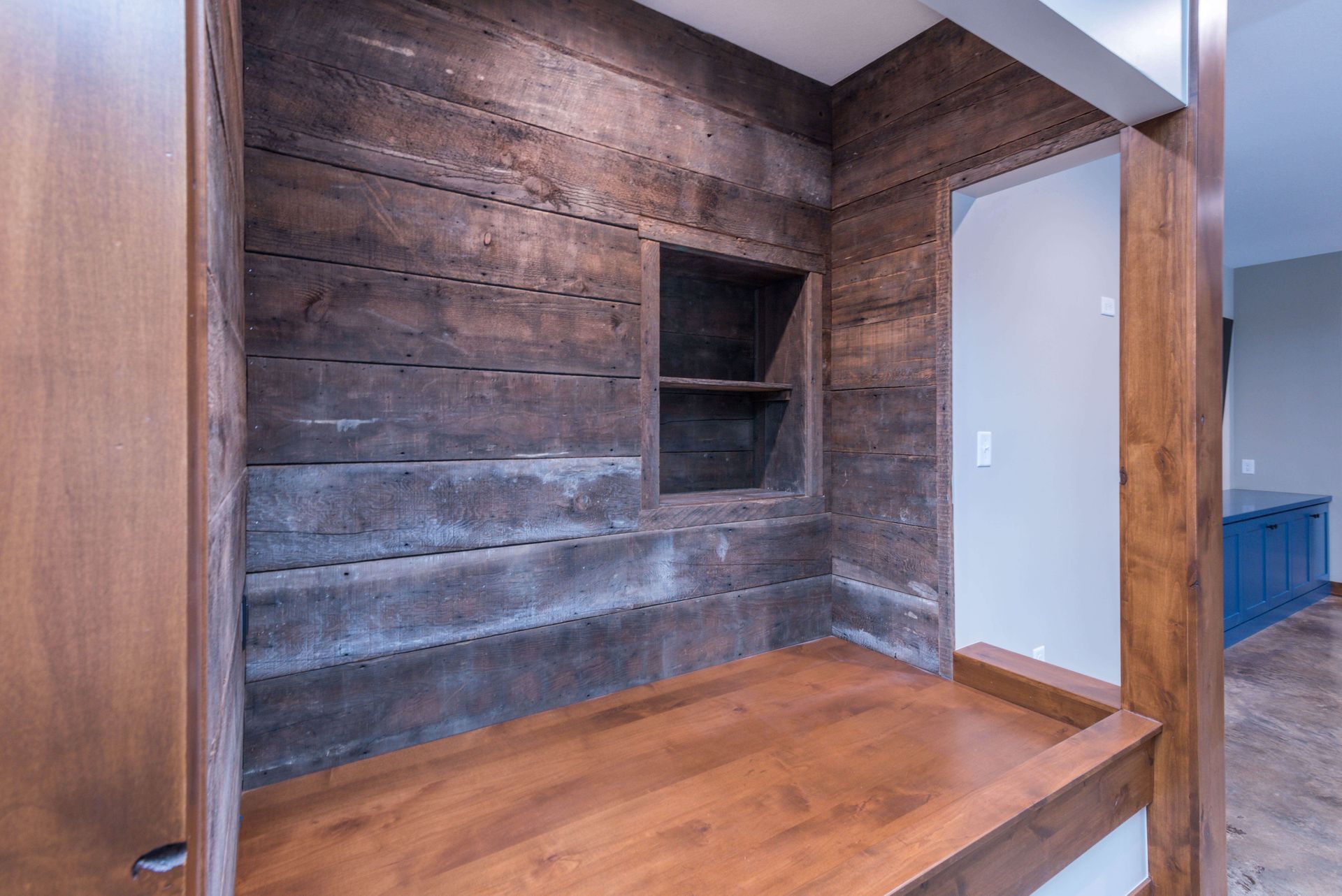 Built-in wooden desk and shelving nook with rustic, brown wood paneling.