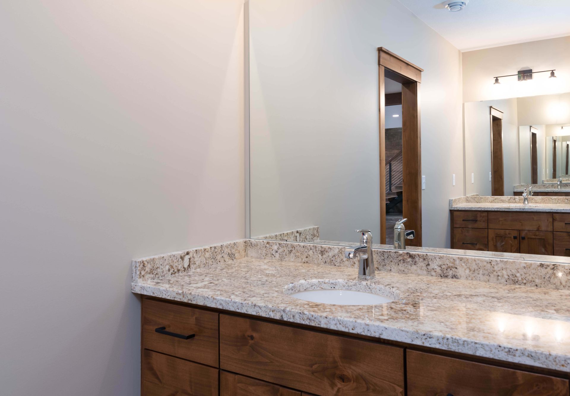 Bathroom with granite countertop, wooden cabinets, and a mirror.