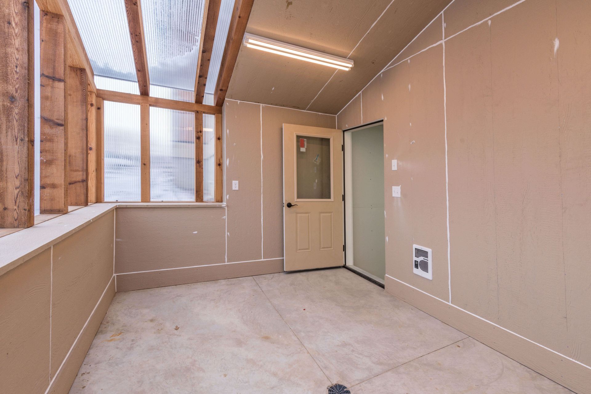 Interior of unfinished room with a door, window, and a concrete floor.