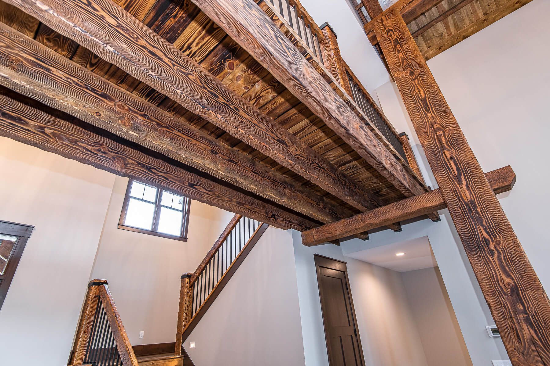 Wooden beams and staircase in a building with a window, visible from a low angle.