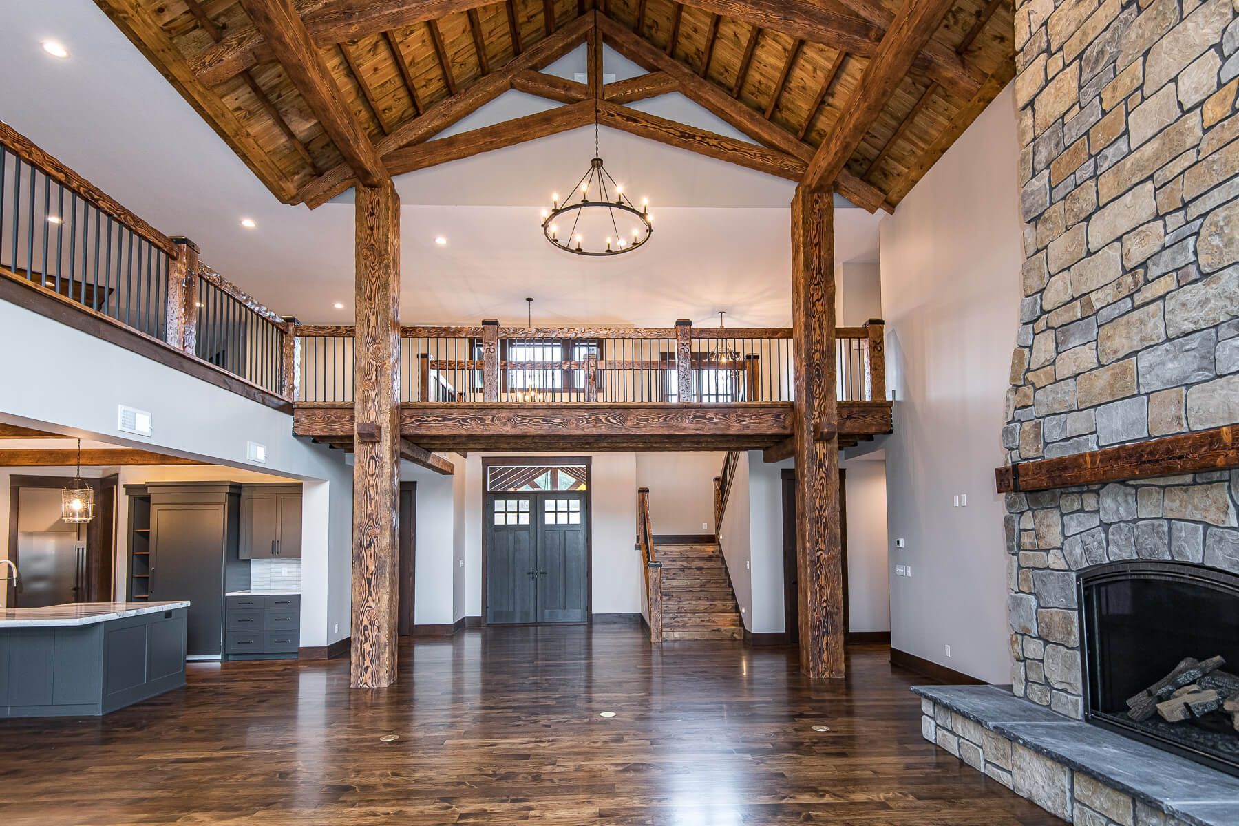 Spacious living room with exposed wood beams, stone fireplace, and a loft.