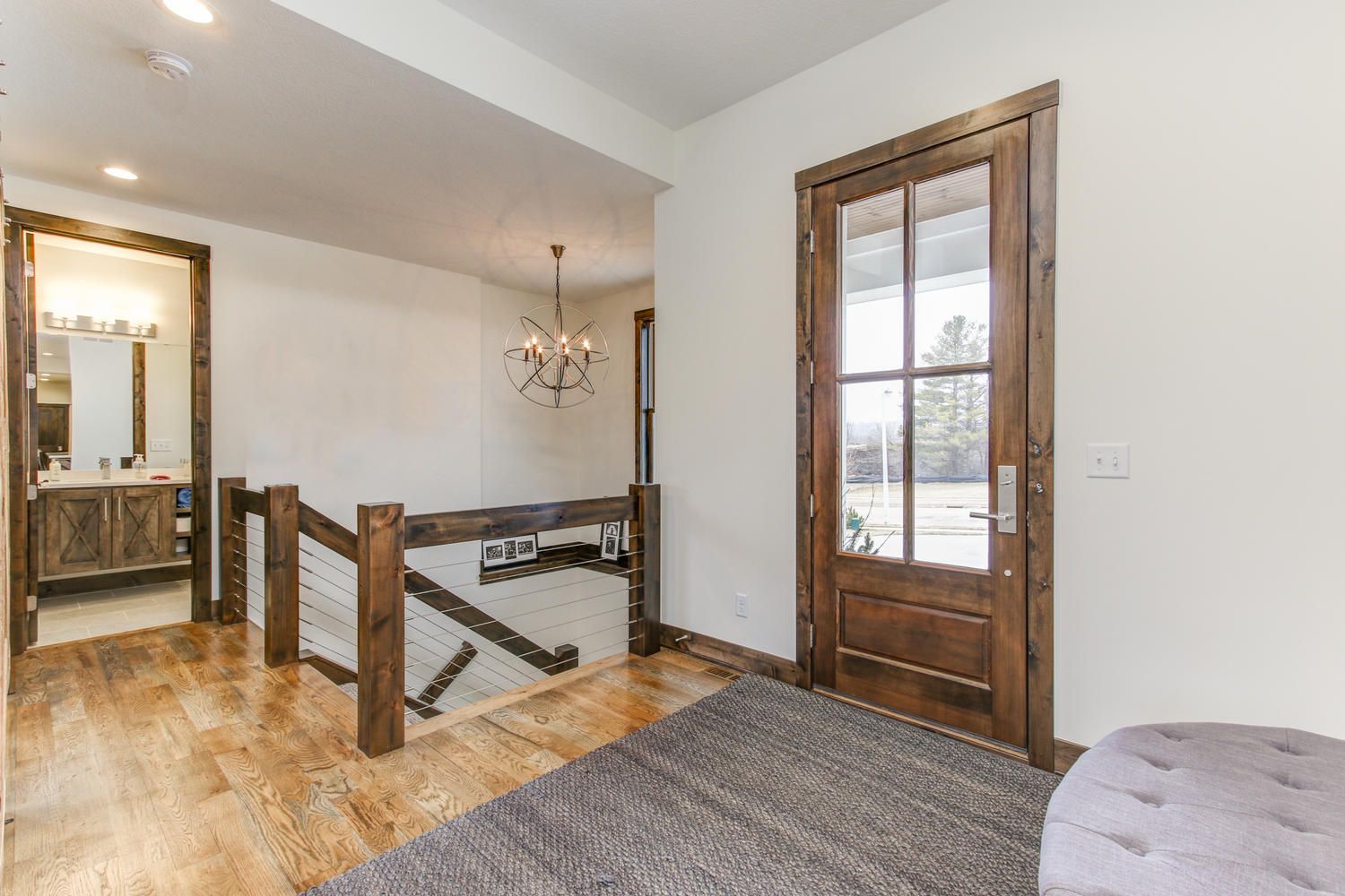 Entryway with wooden door, hardwood floor, open railing, and chandelier.