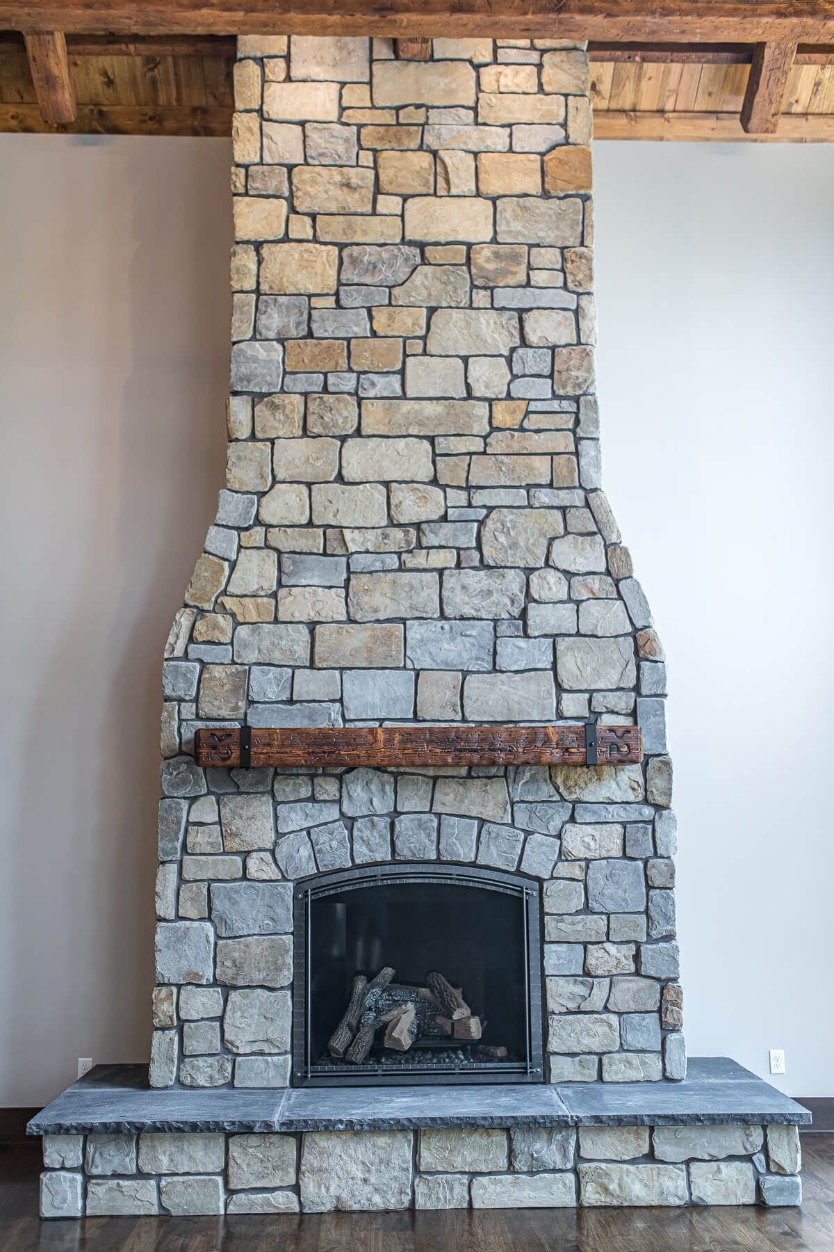 Stone fireplace with curved design, wooden mantel, and firebox.