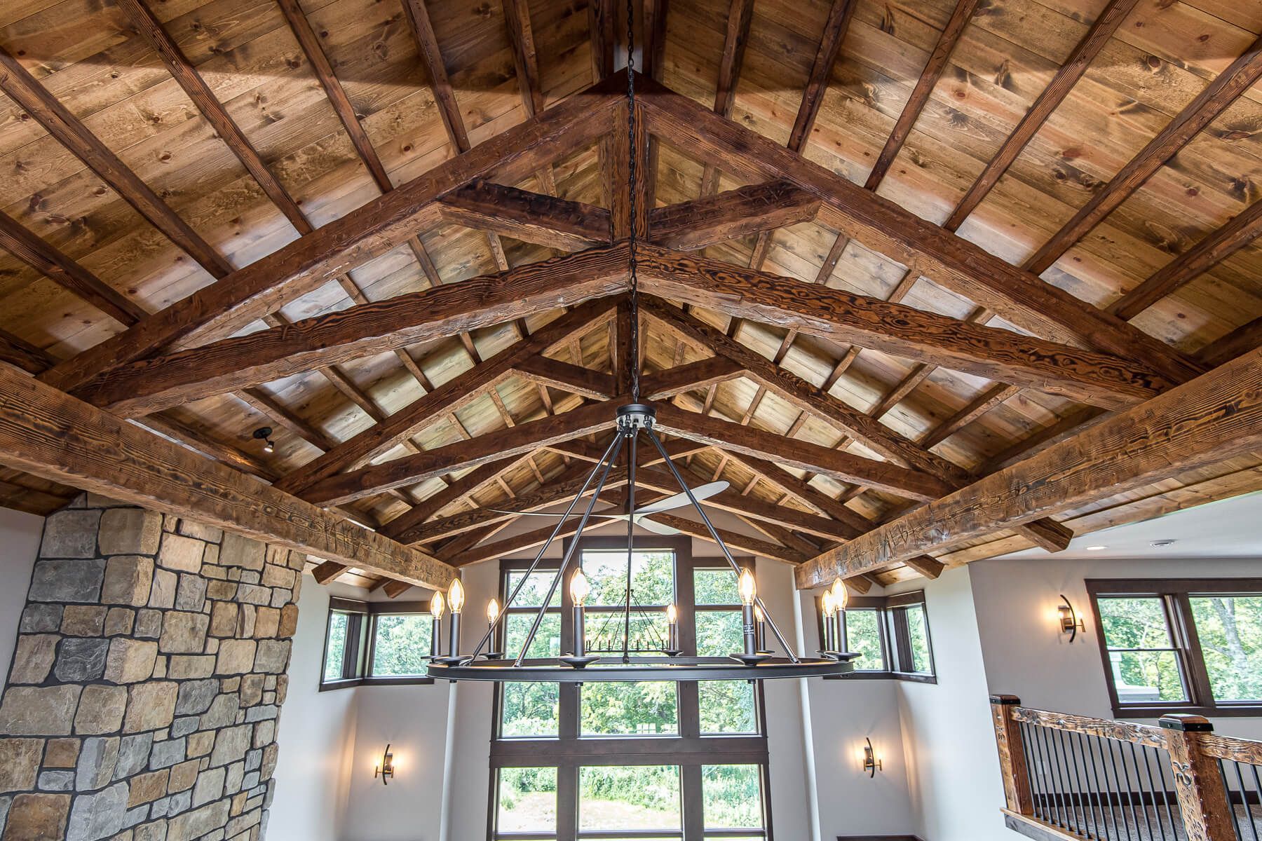 Wooden vaulted ceiling with exposed beams, centered chandelier, windows.