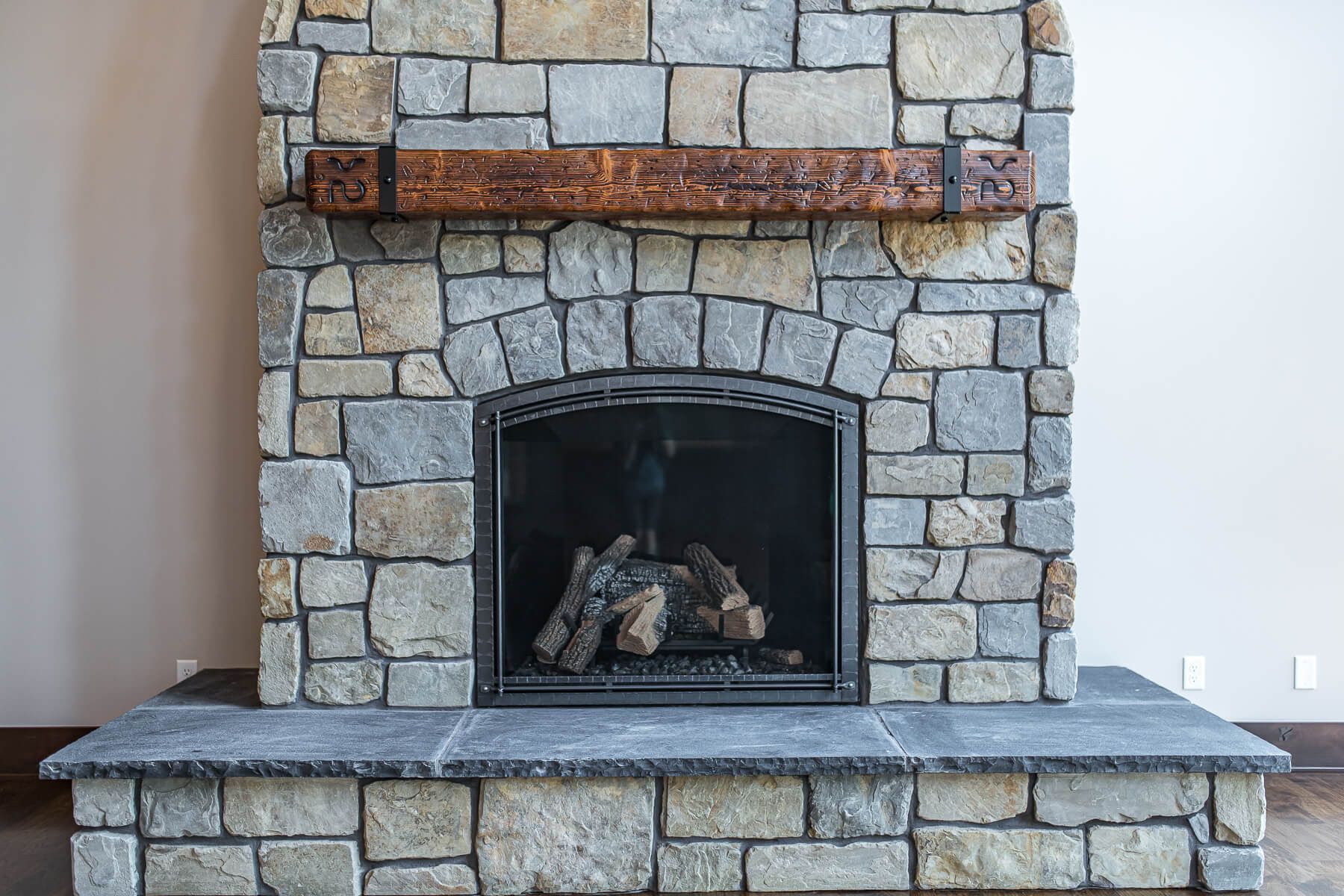 Stone fireplace with wooden beam mantel, hearth, and fire screen.