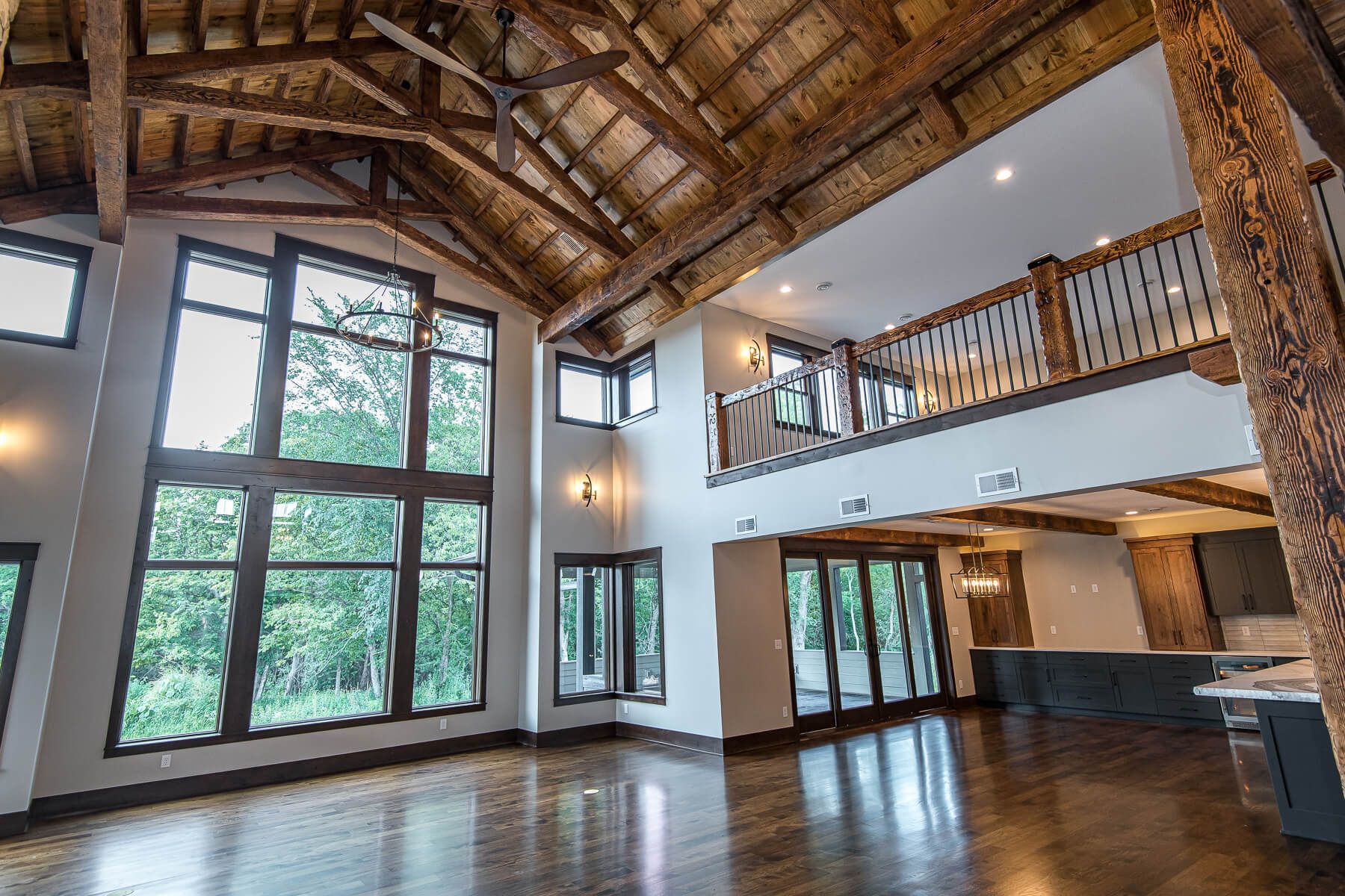Spacious interior with exposed wooden beams, large windows, and a loft area.