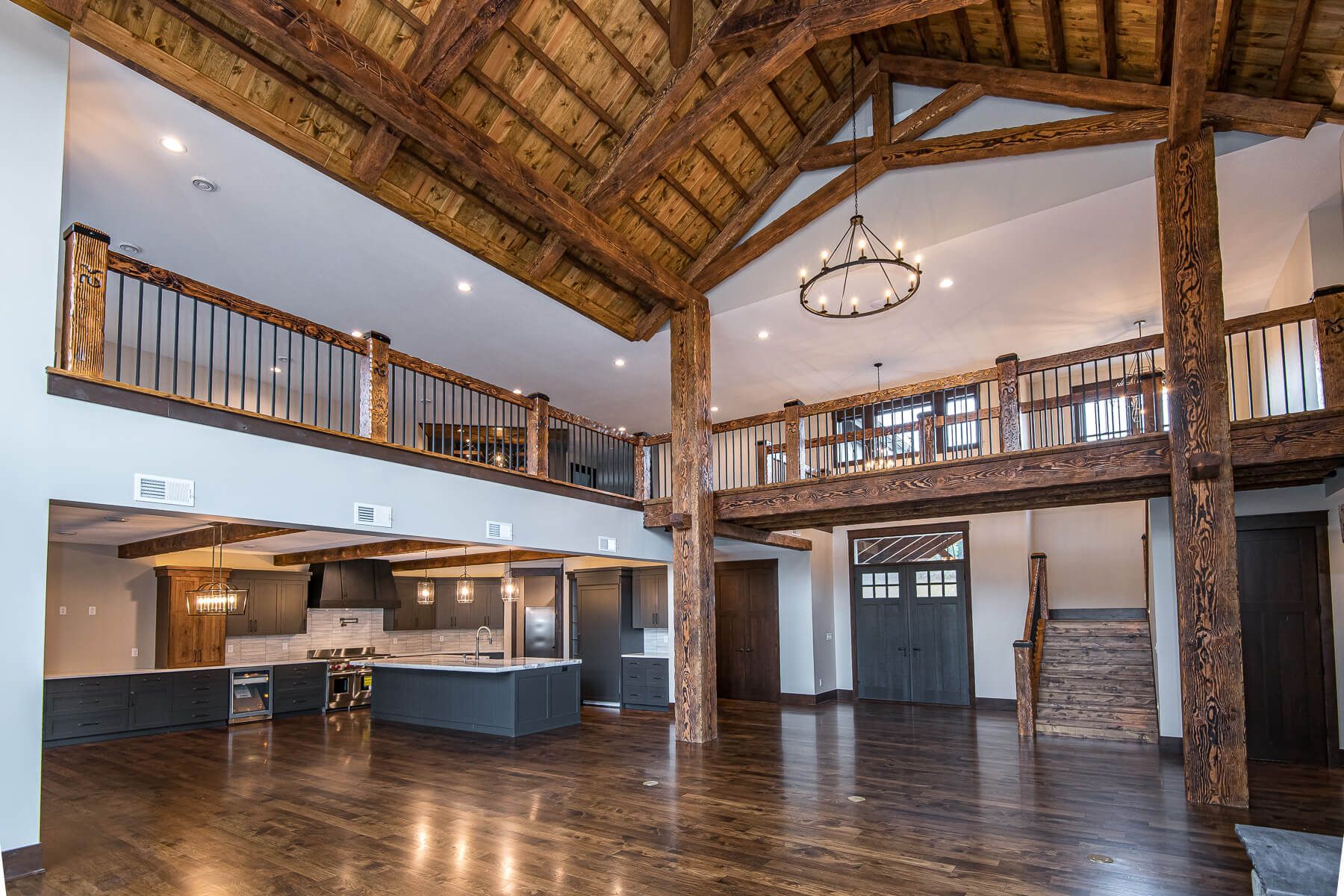 Spacious interior with exposed wooden beams, a loft, and a kitchen with an island.