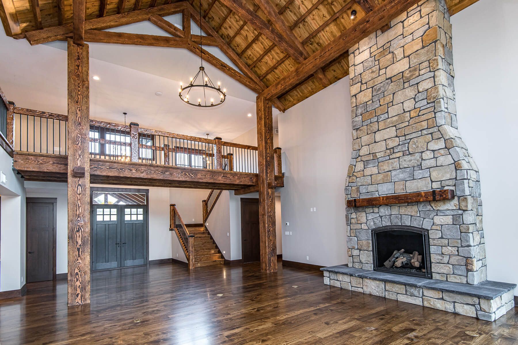 Spacious room with wood beams, stone fireplace, and a loft.