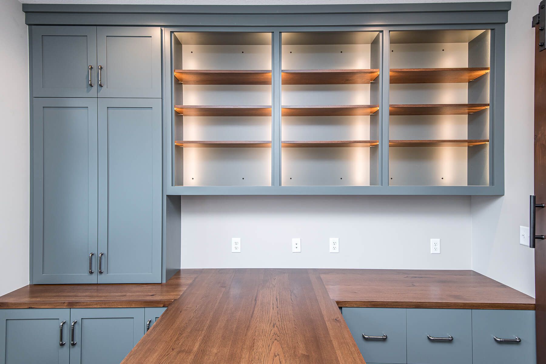 Built-in blue cabinets with wood countertops and shelves.