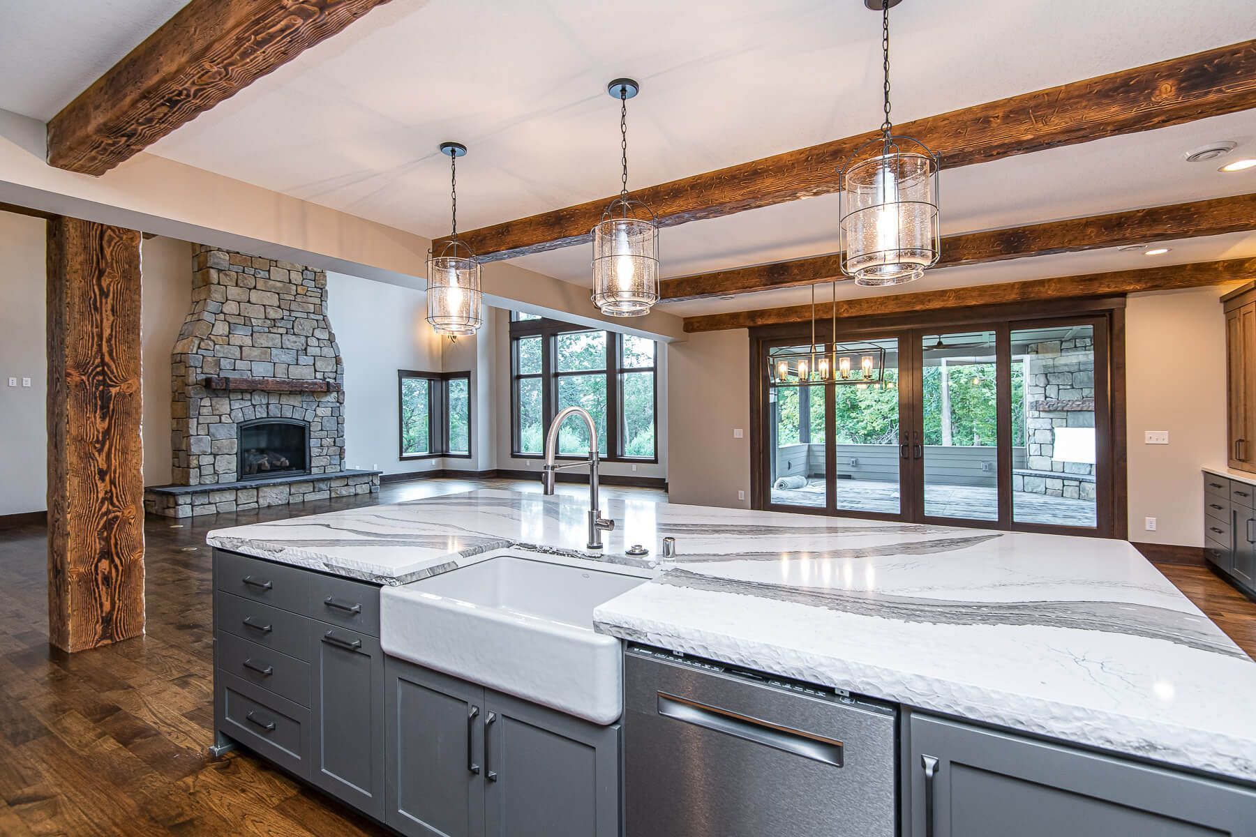 Kitchen with island, stone fireplace, wood beams, and large windows.