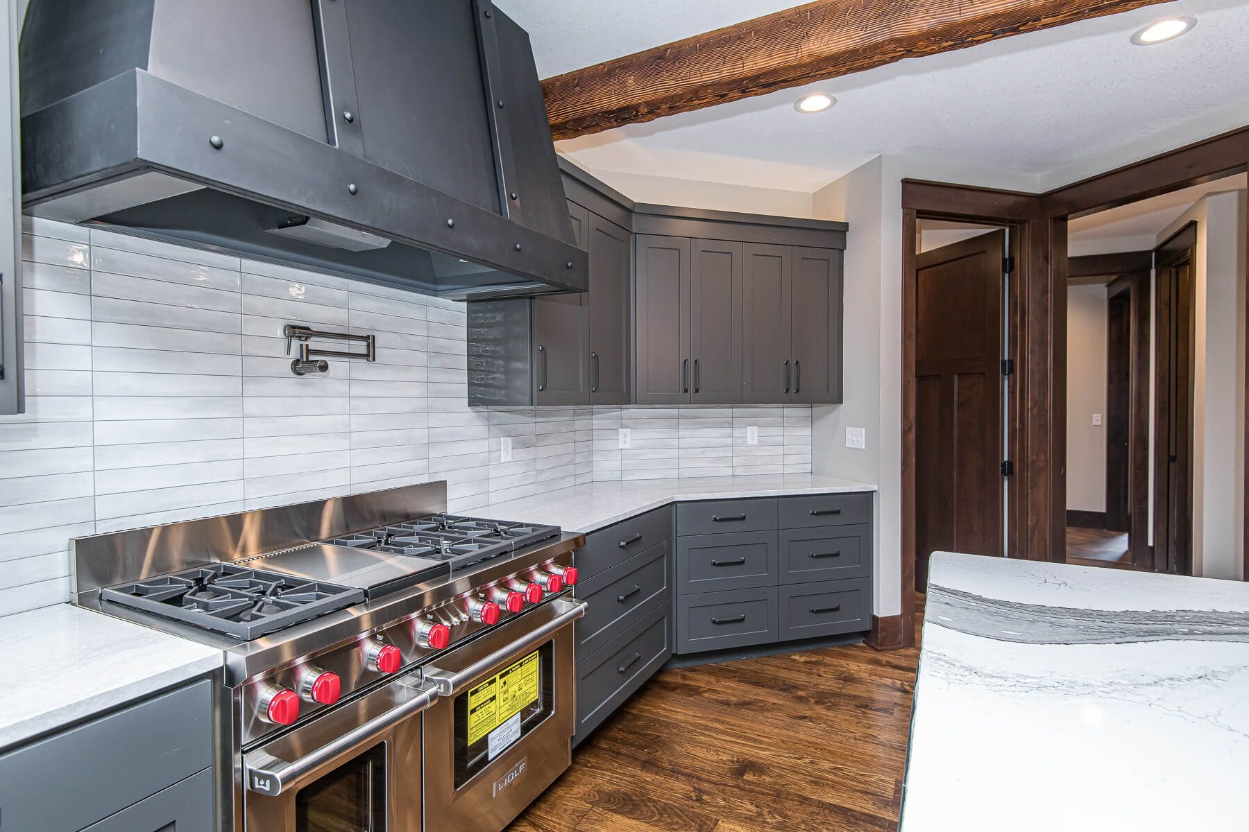 Modern kitchen with grey cabinets, stainless steel range, and white tile backsplash.