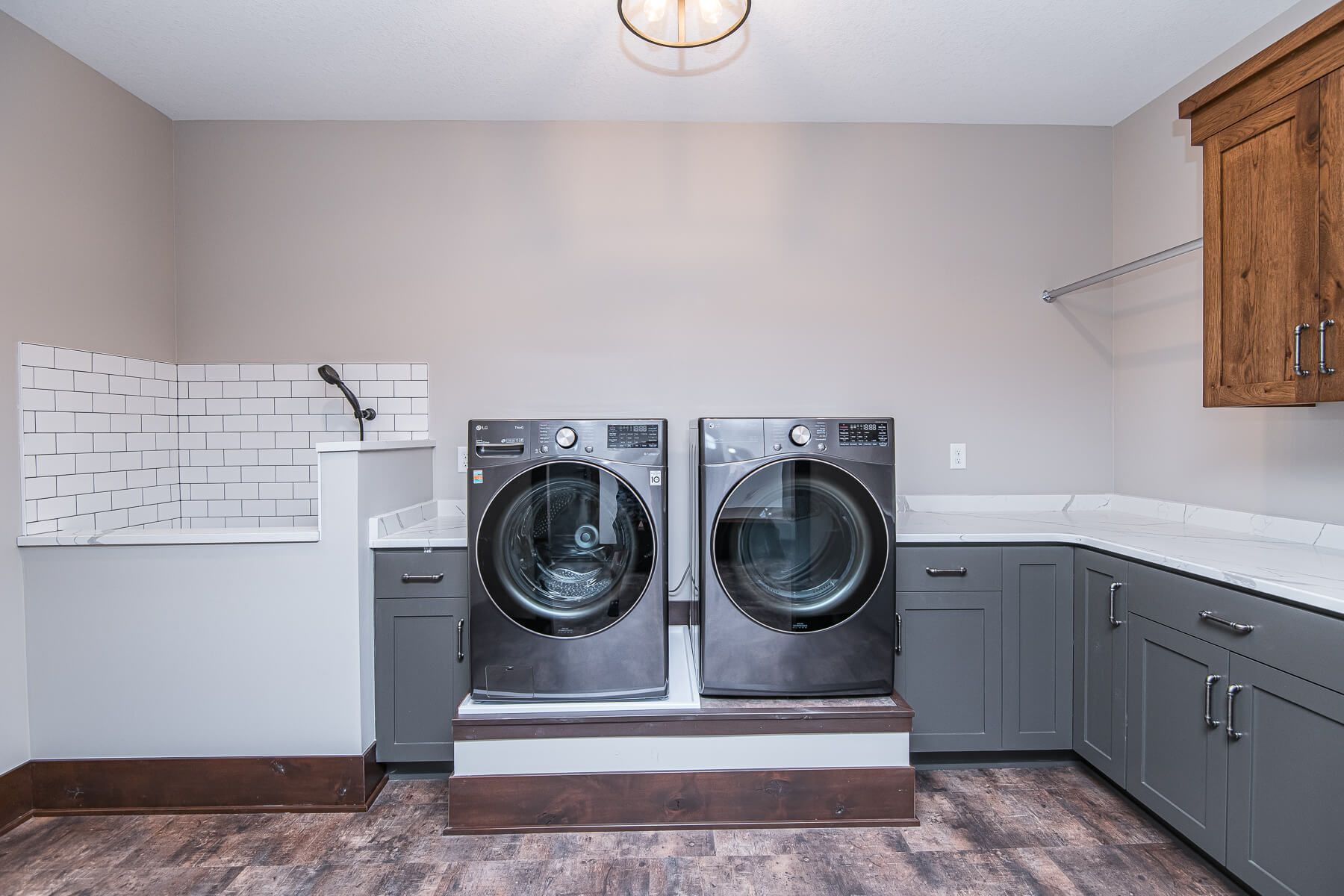 Laundry room with gray washer and dryer, cabinets, and a dog wash station.
