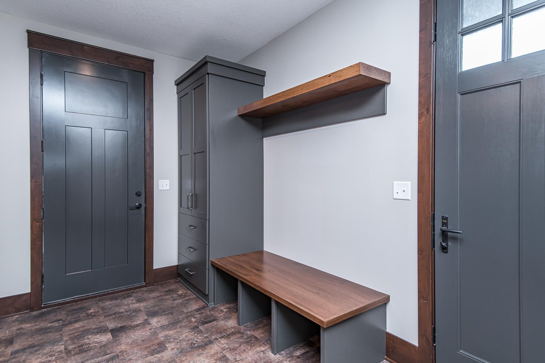 Gray entryway with a dark wood door, cabinet, and bench.