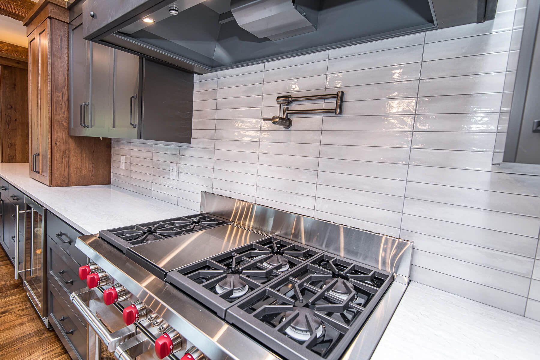 Stainless steel gas range in modern kitchen with white tile backsplash.