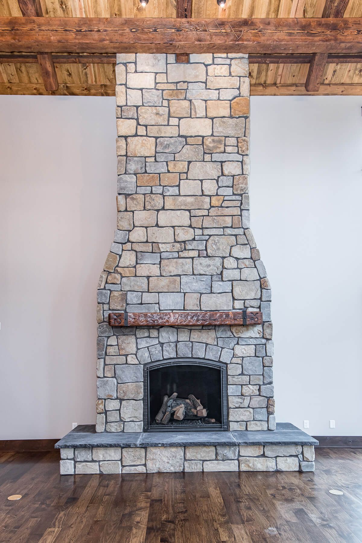 Stone fireplace in a room with wood ceiling and floor.
