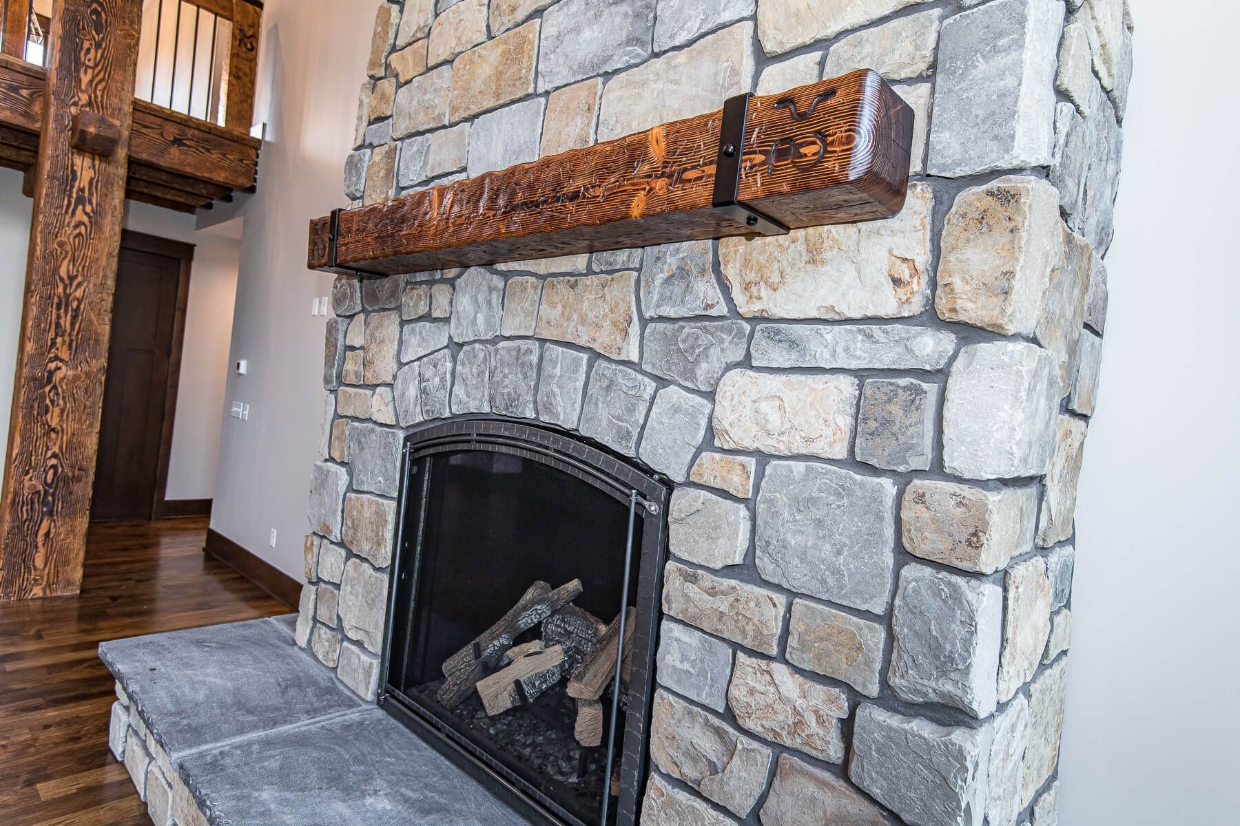 Stone fireplace with wooden mantel. Fireplace features an arched opening.