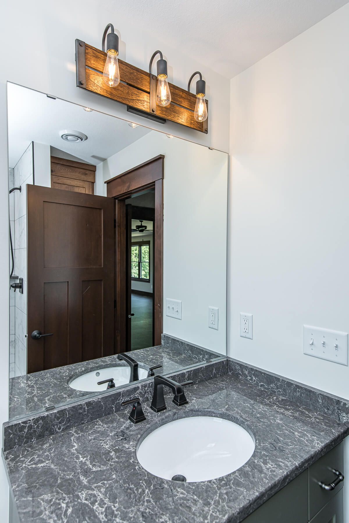 Bathroom with a mirror over a sink, dark countertop, and rustic light fixture.