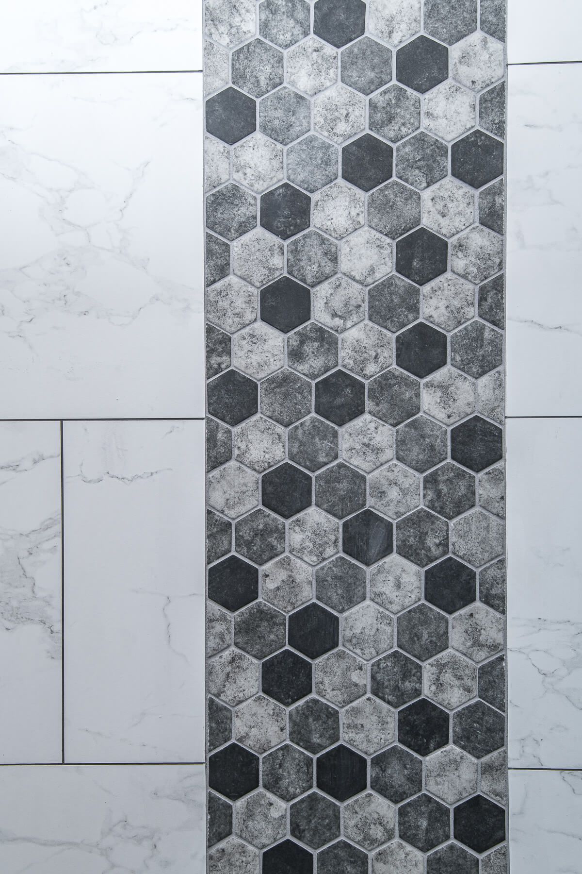 Vertical wall with white rectangular tiles and a central strip of gray and black hexagon tiles.