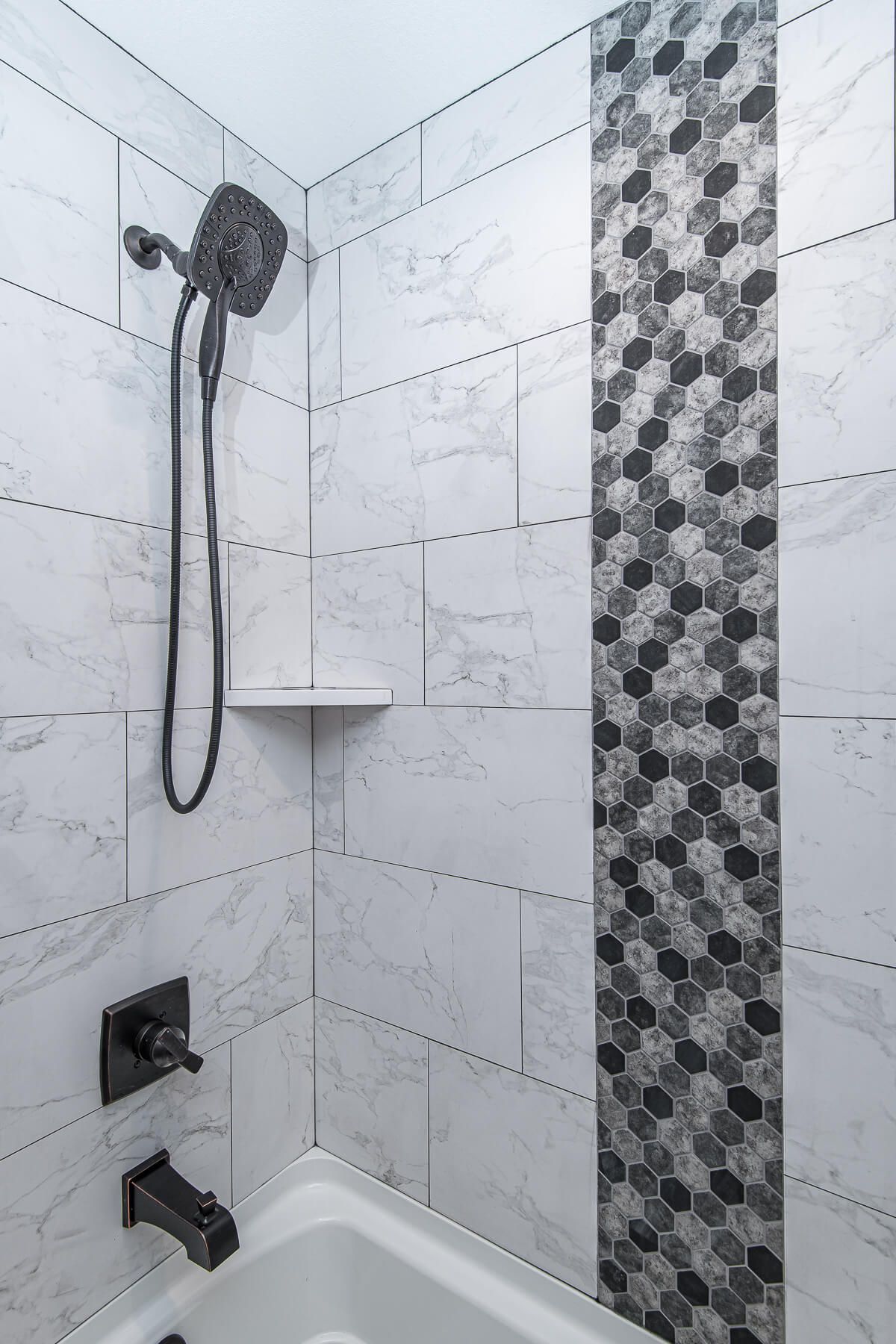 Shower with white and gray marble tiles, black fixtures, and a decorative hexagonal accent.