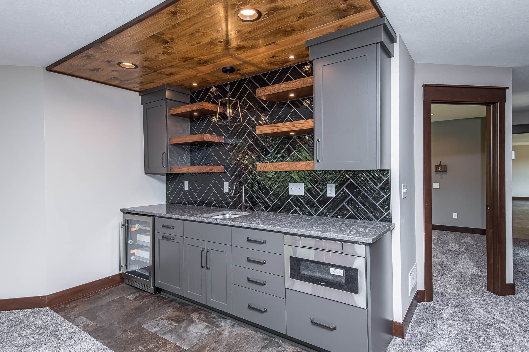 Gray bar area with dark backsplash, wooden shelves, and a microwave.
