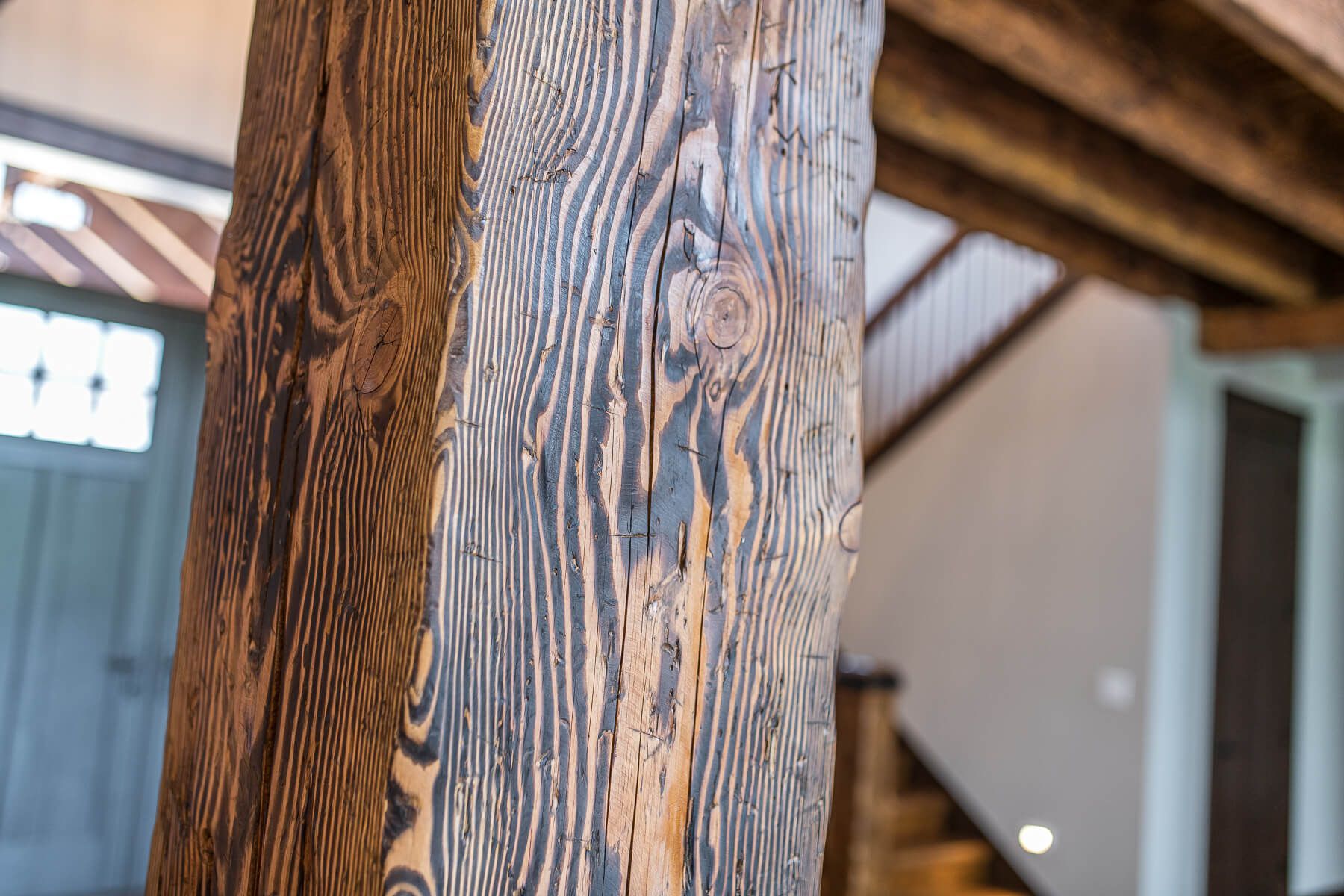 Close-up of a weathered wooden support beam, featuring visible grain patterns and knots.