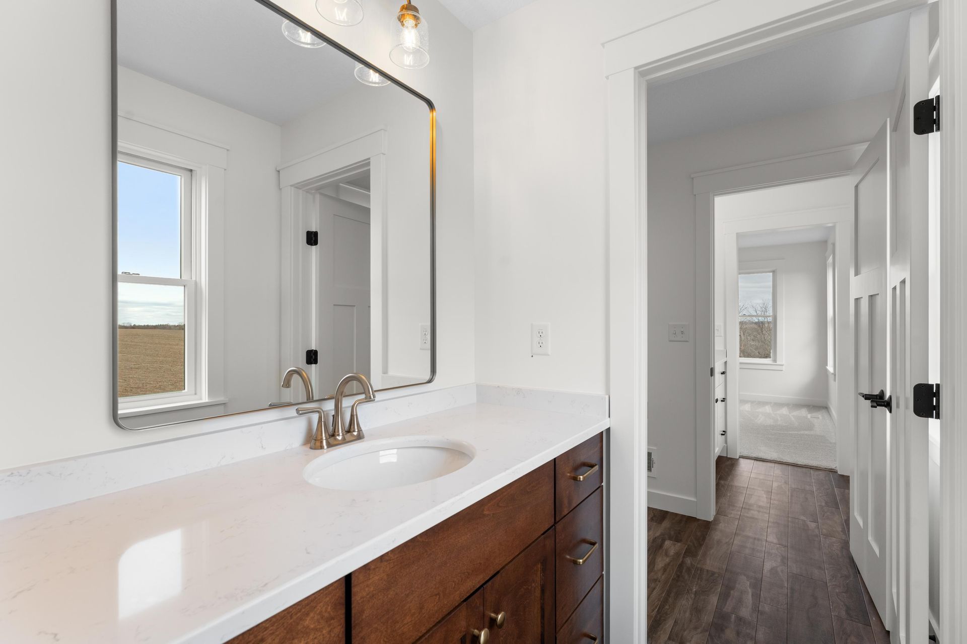 Bathroom with a vanity, large mirror, and open doorway to hallway.