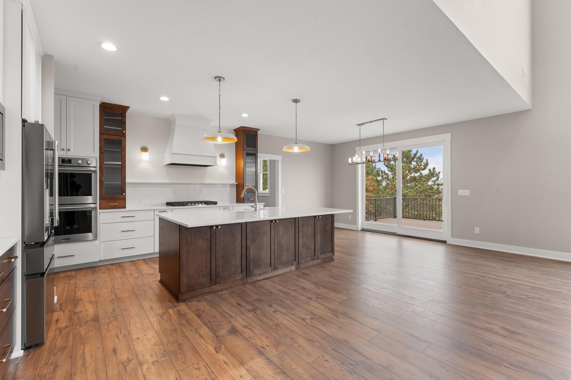 Modern kitchen with dark wood island and cabinets, white countertops, and sliding glass doors to a balcony.