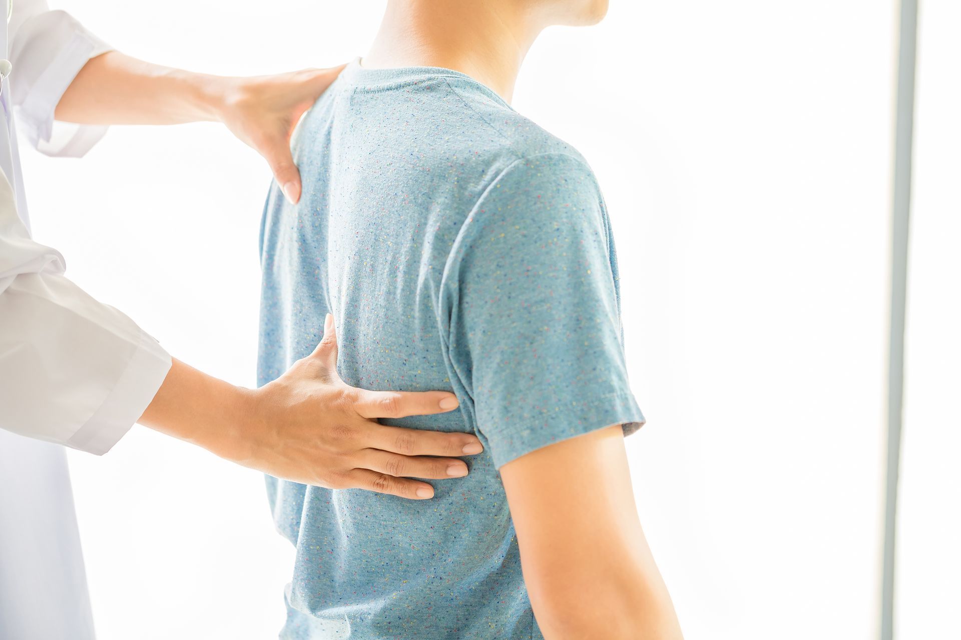 A man is getting his back examined by a physiotherapist.
