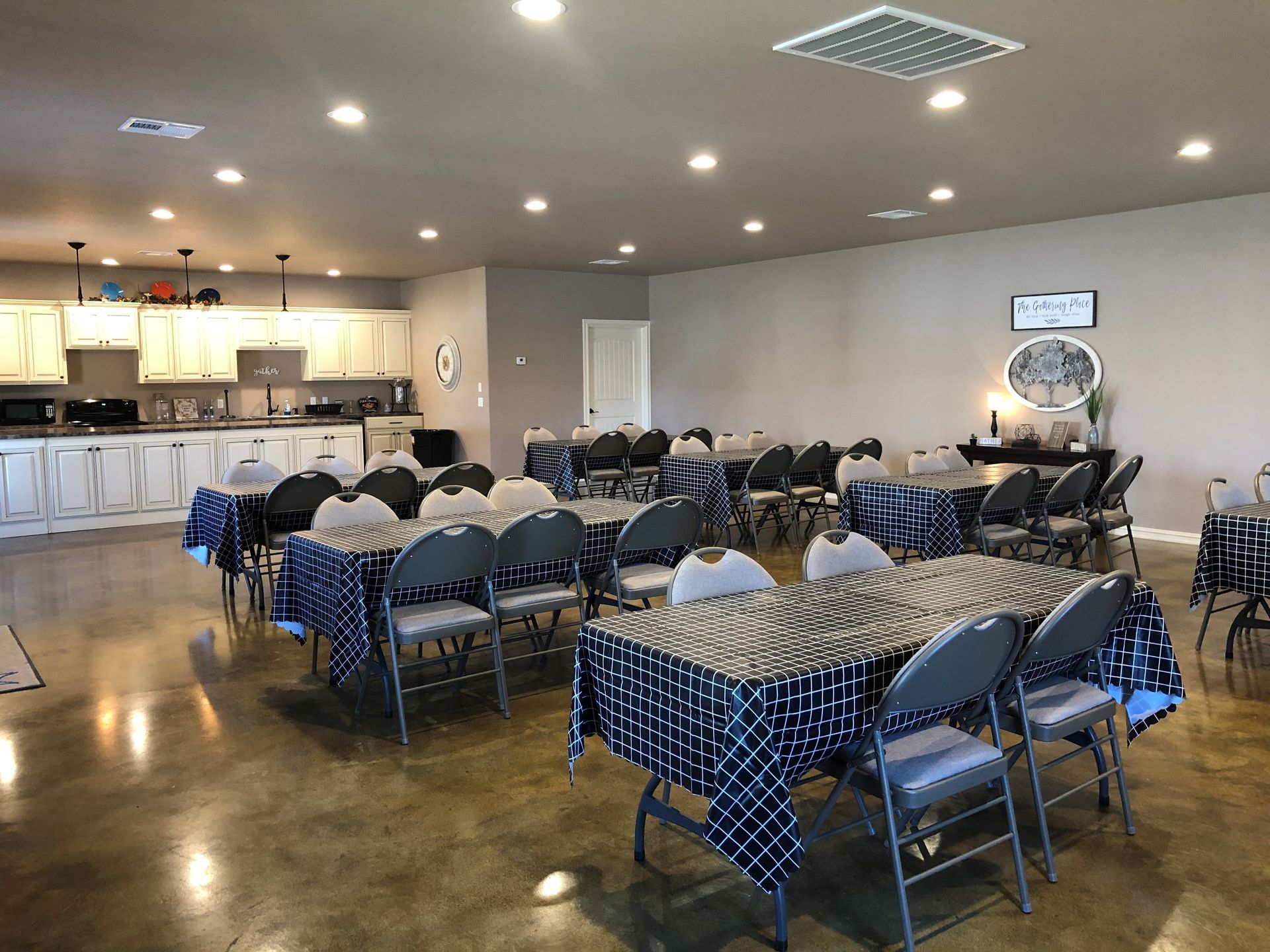 Banquet hall with round tables and chairs set for an event, with a buffet area in the back