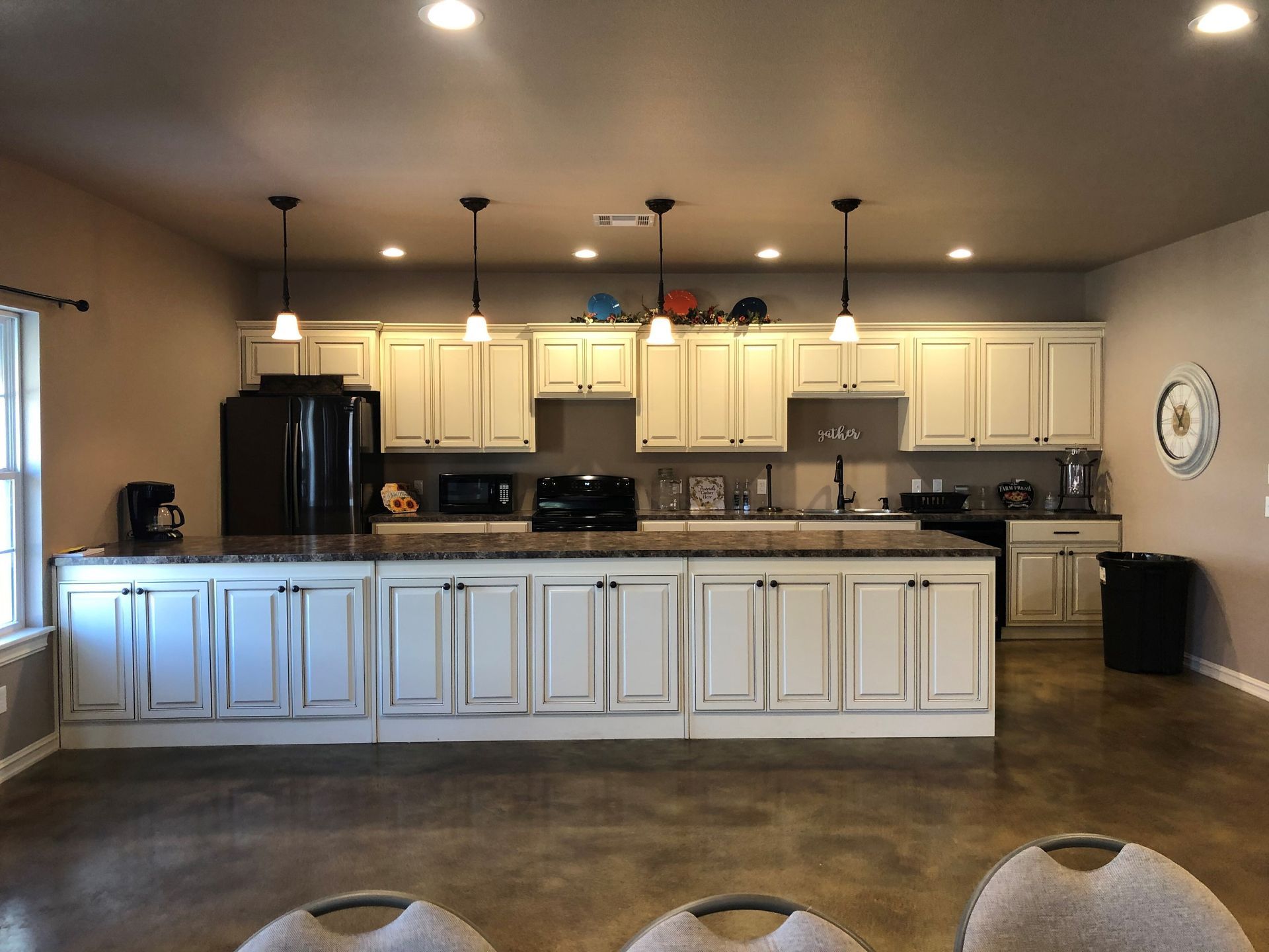 Modern kitchen with white cabinets, black appliances, island, and concrete floor
