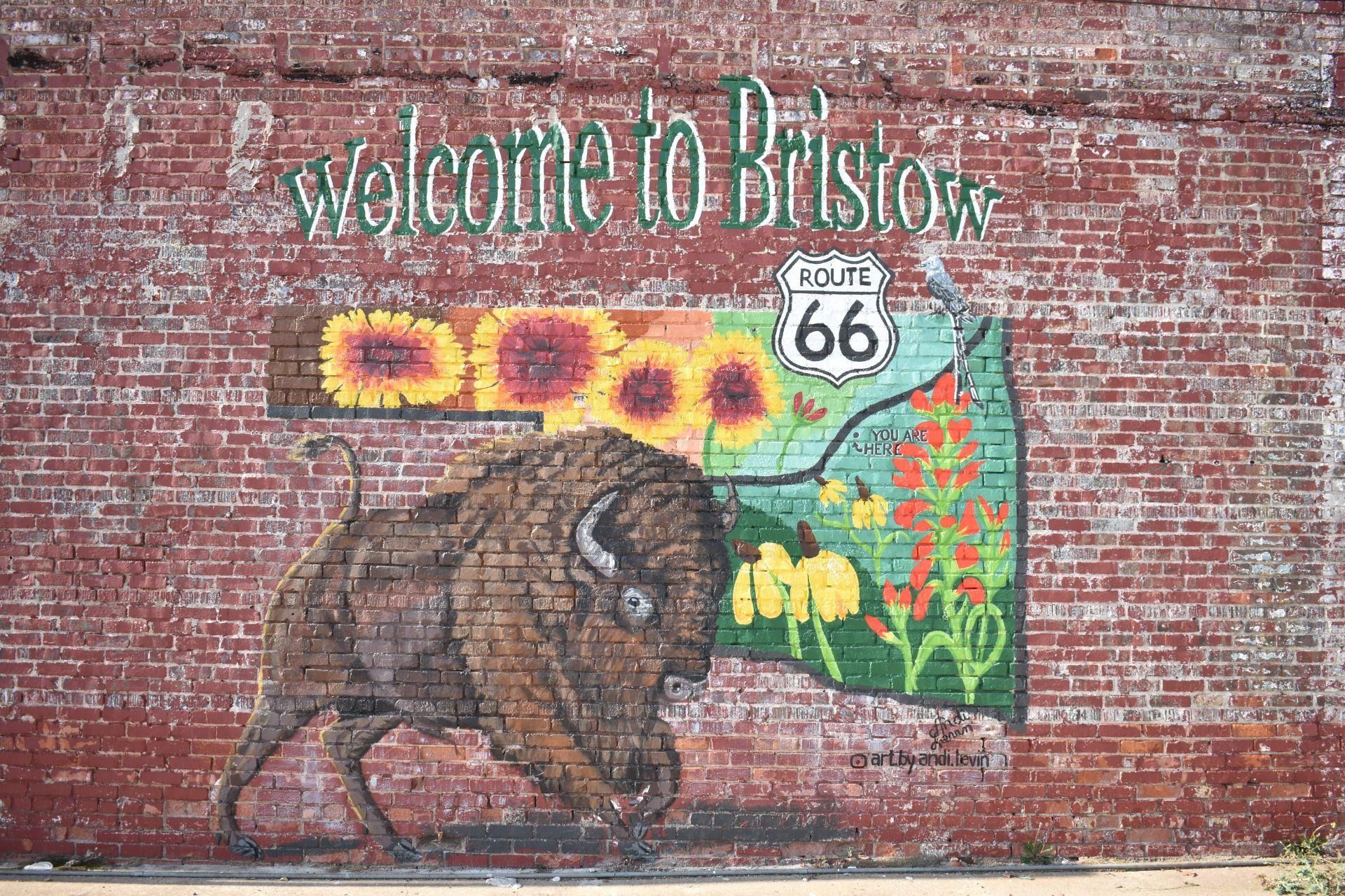 Mural on brick wall reading “Welcome to Bristol” with a bison, sunflowers, and Route 66 sign