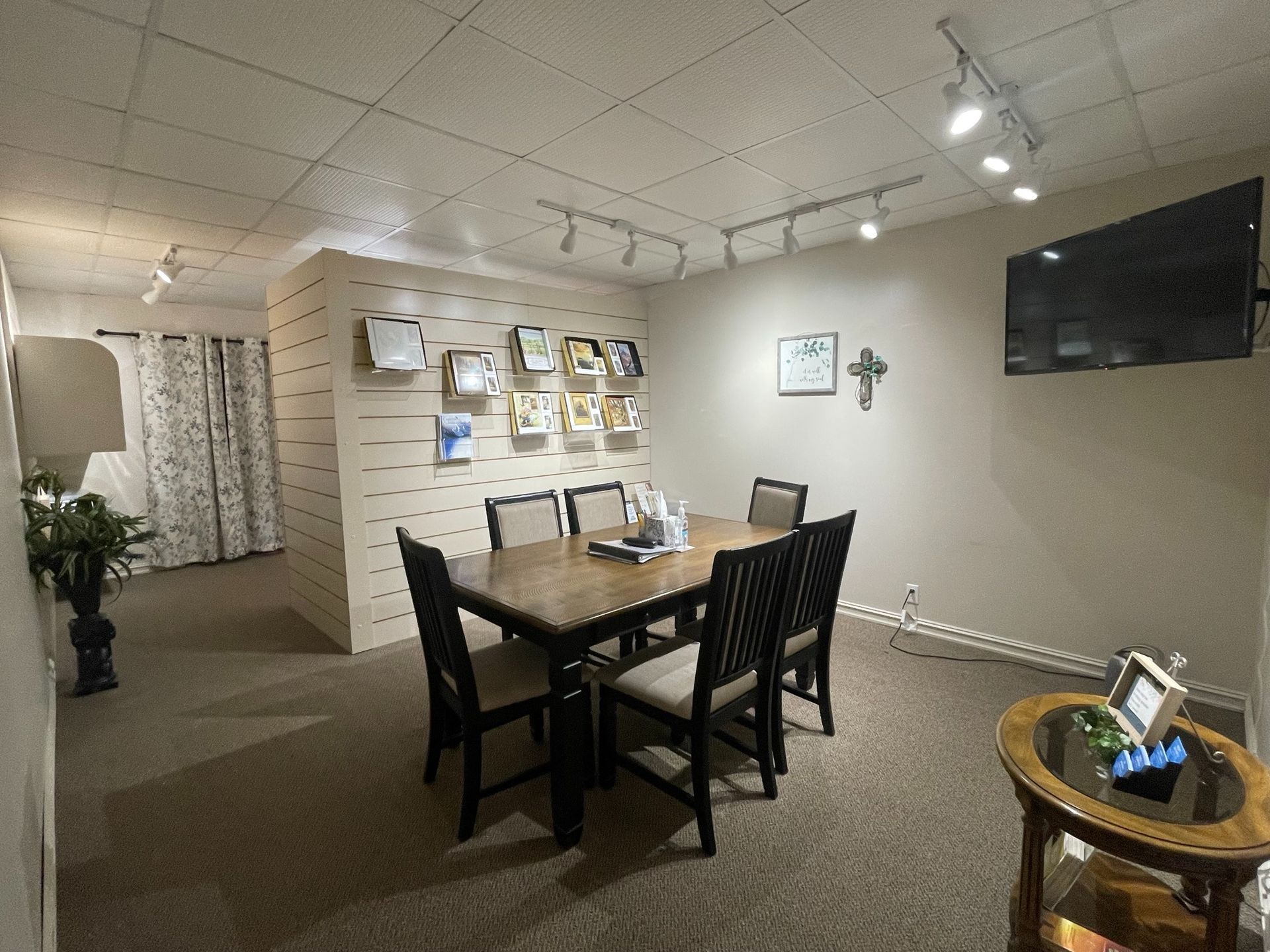 Gallery room with display wall, dining table, and TV on beige carpeted floor