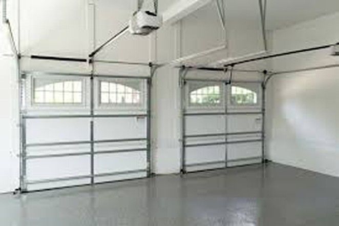 An empty garage with two garage doors and a garage door opener.