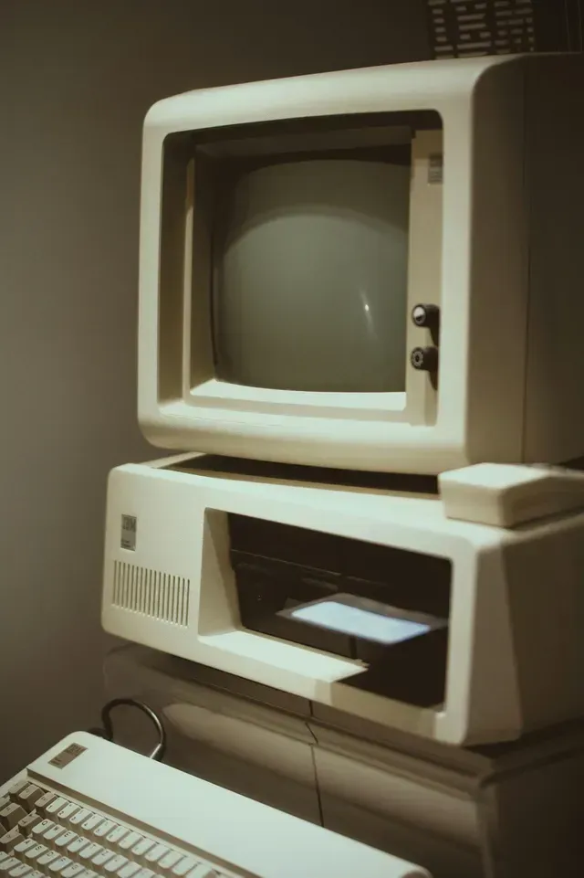 An old computer is stacked on top of another computer
