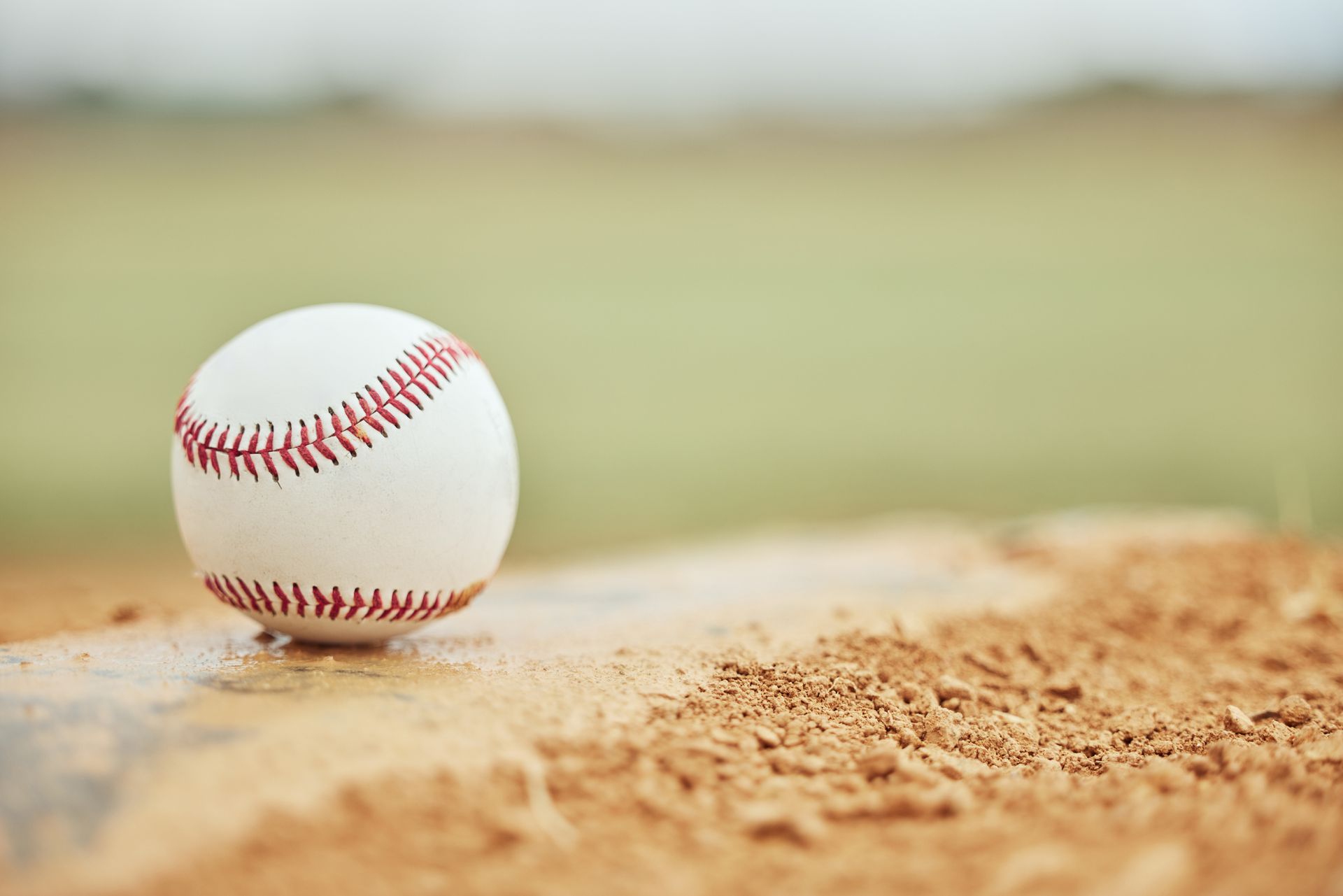 A baseball is sitting on top of a dirt field.