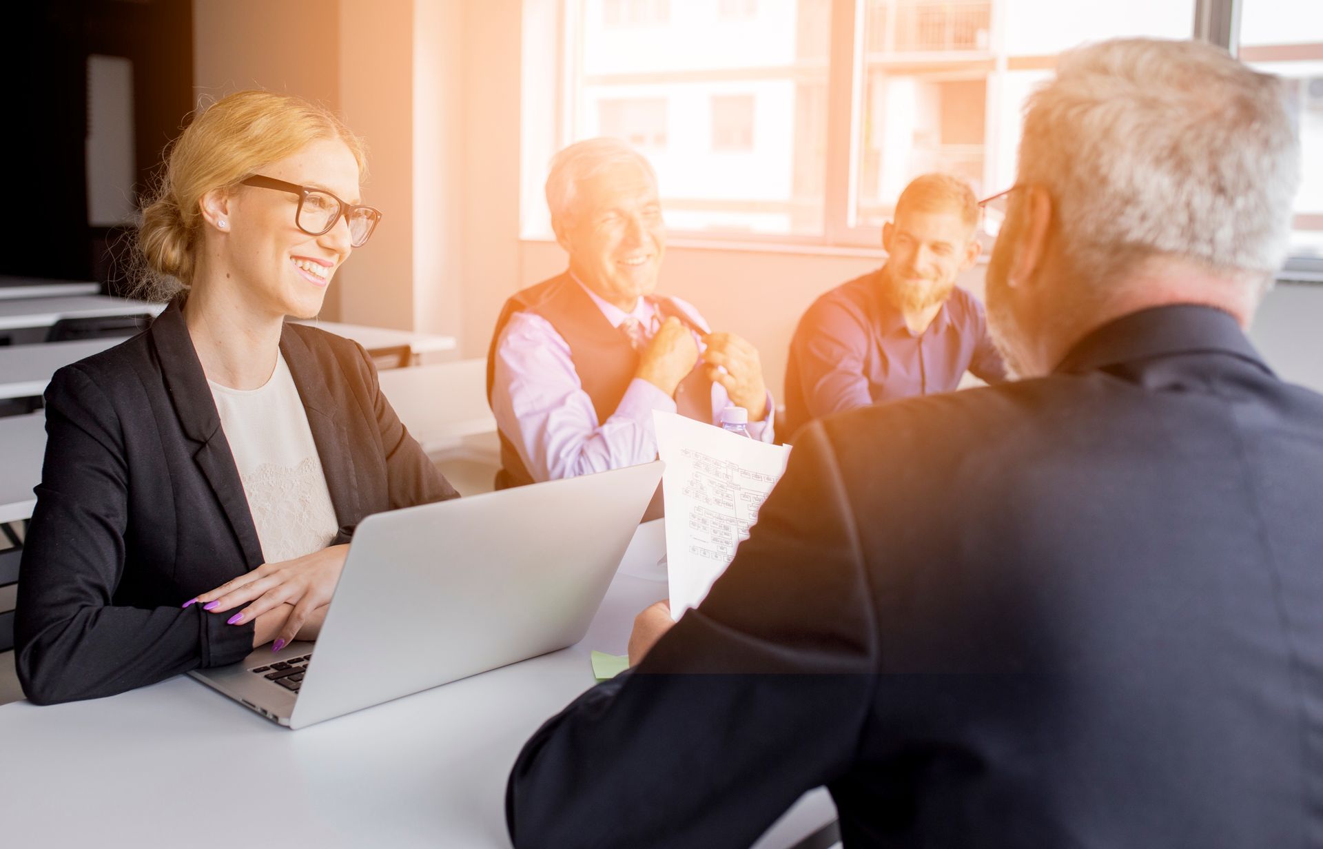 A group of people are sitting at a table with laptops.