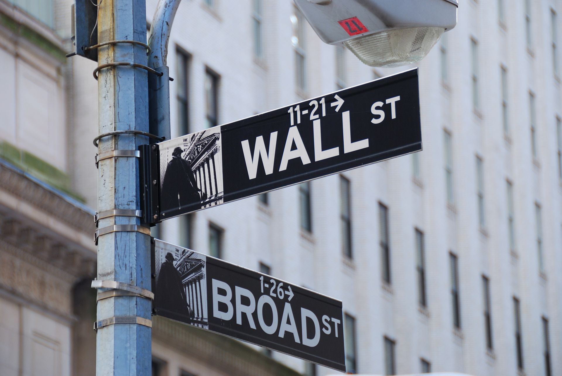 A street sign for wall street and broad street is on a pole.