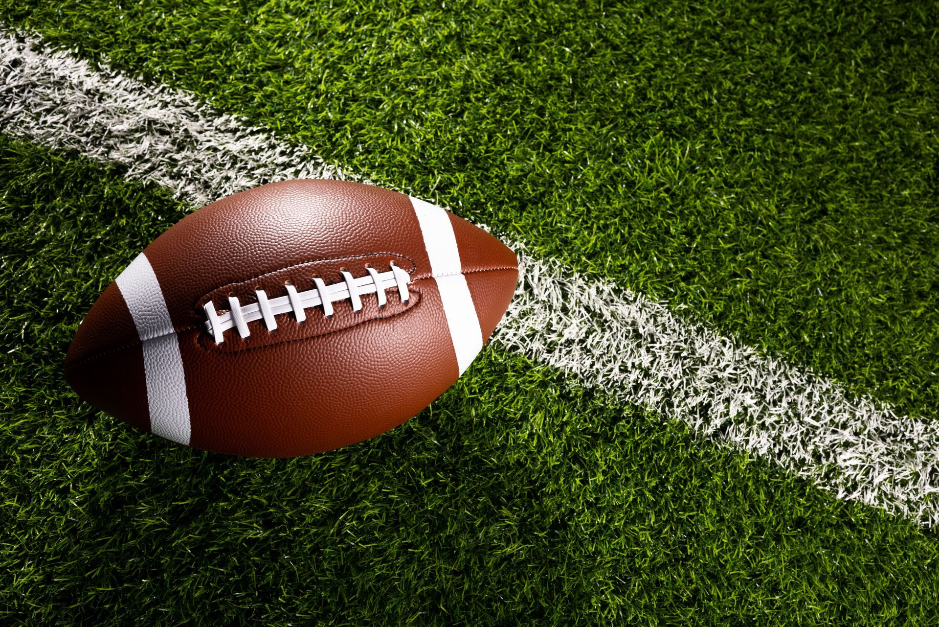 A football is on the sideline of a soccer field.