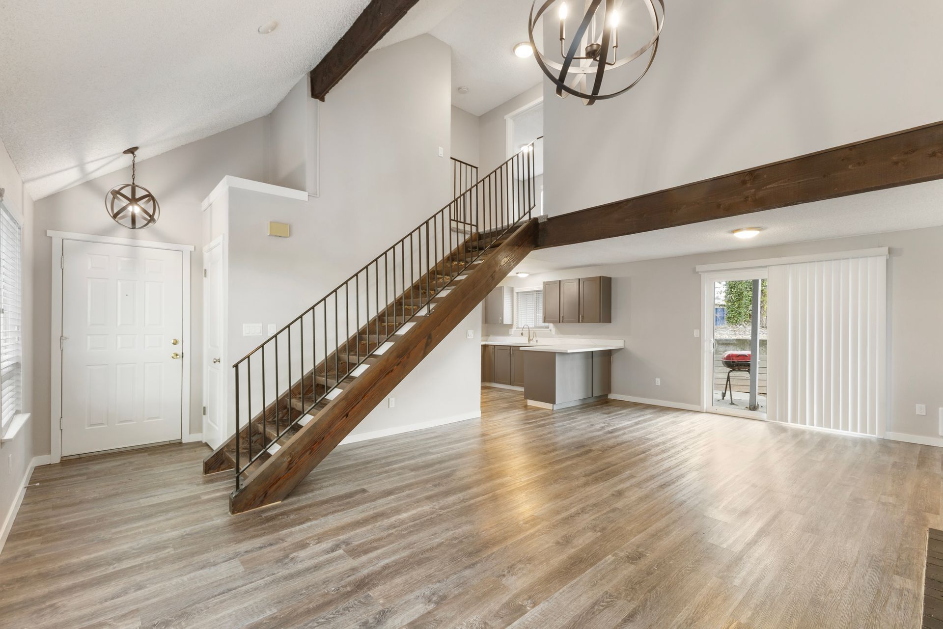 An empty living room with a wooden staircase leading up to the second floor.