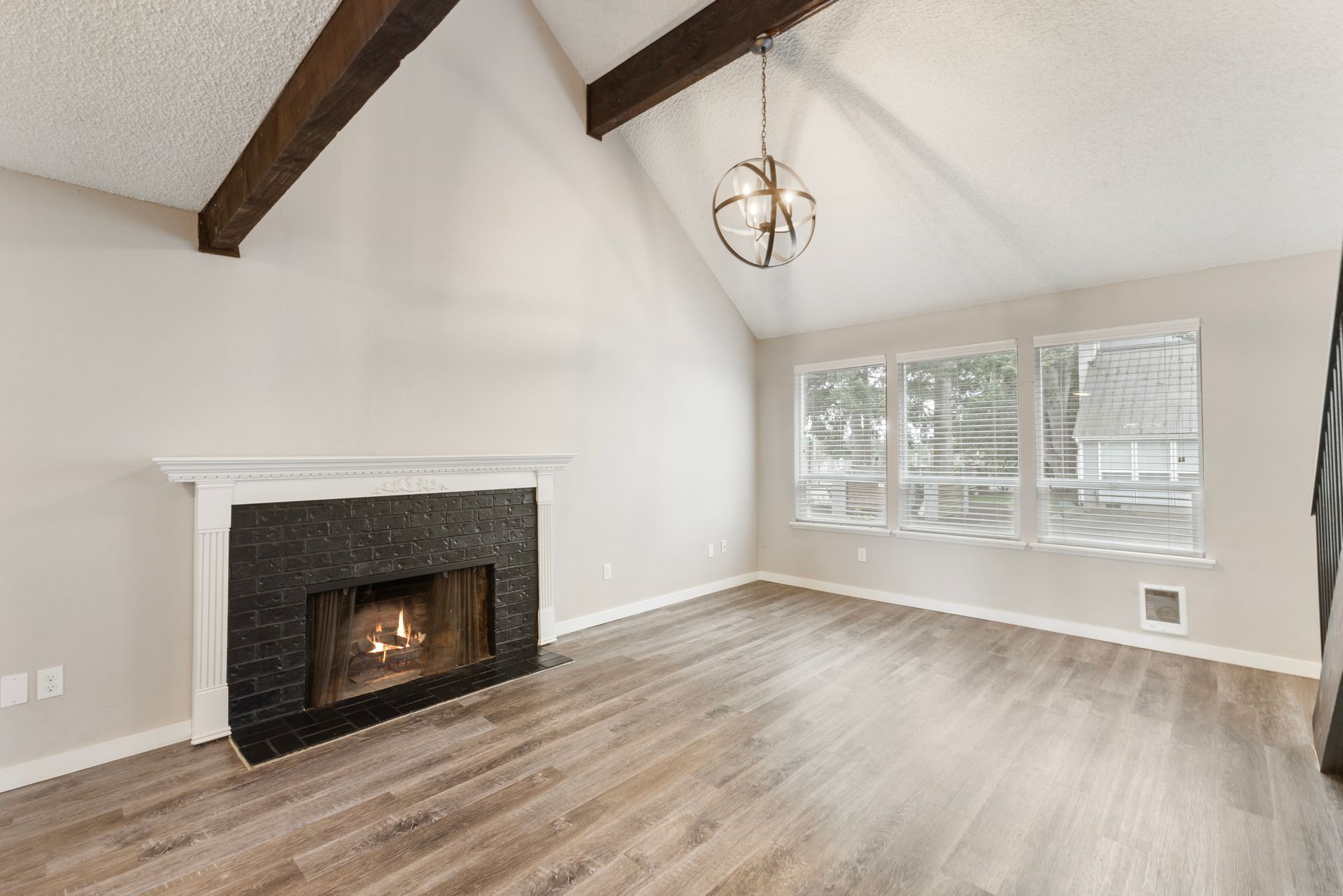 An empty living room with a fireplace and lots of windows.
